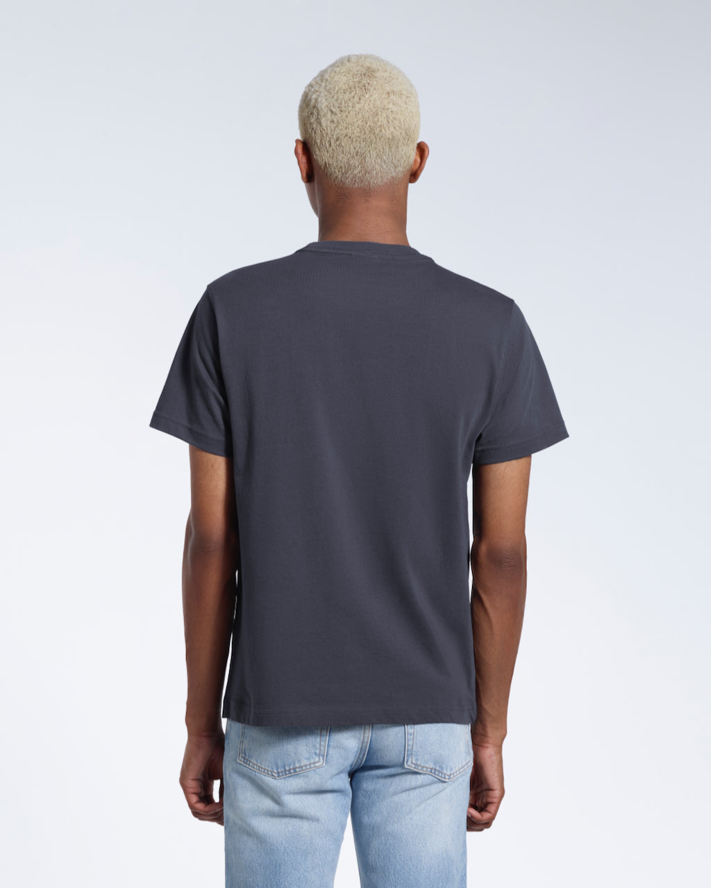 A man facing away from the camera, modelling a plain dark grey short sleeve organic cotton t shirt.