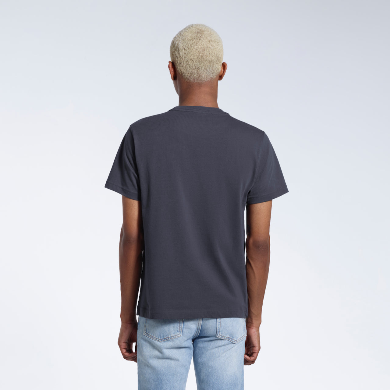 A man facing away from the camera, modelling a plain dark grey short sleeve organic cotton t shirt.