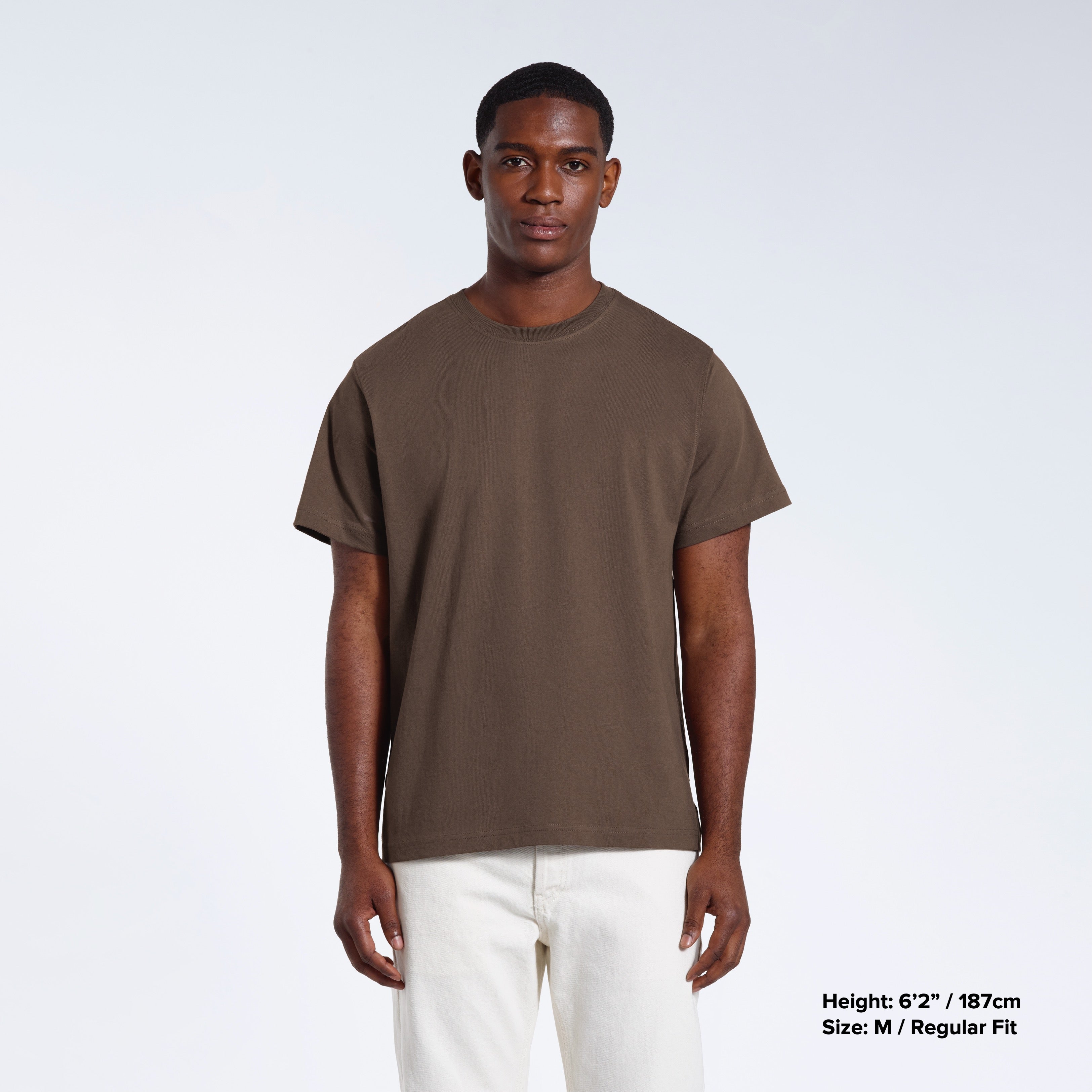 A man facing front on looking into the camera, modelling a plain dark khaki short sleeve organic cotton t shirt.