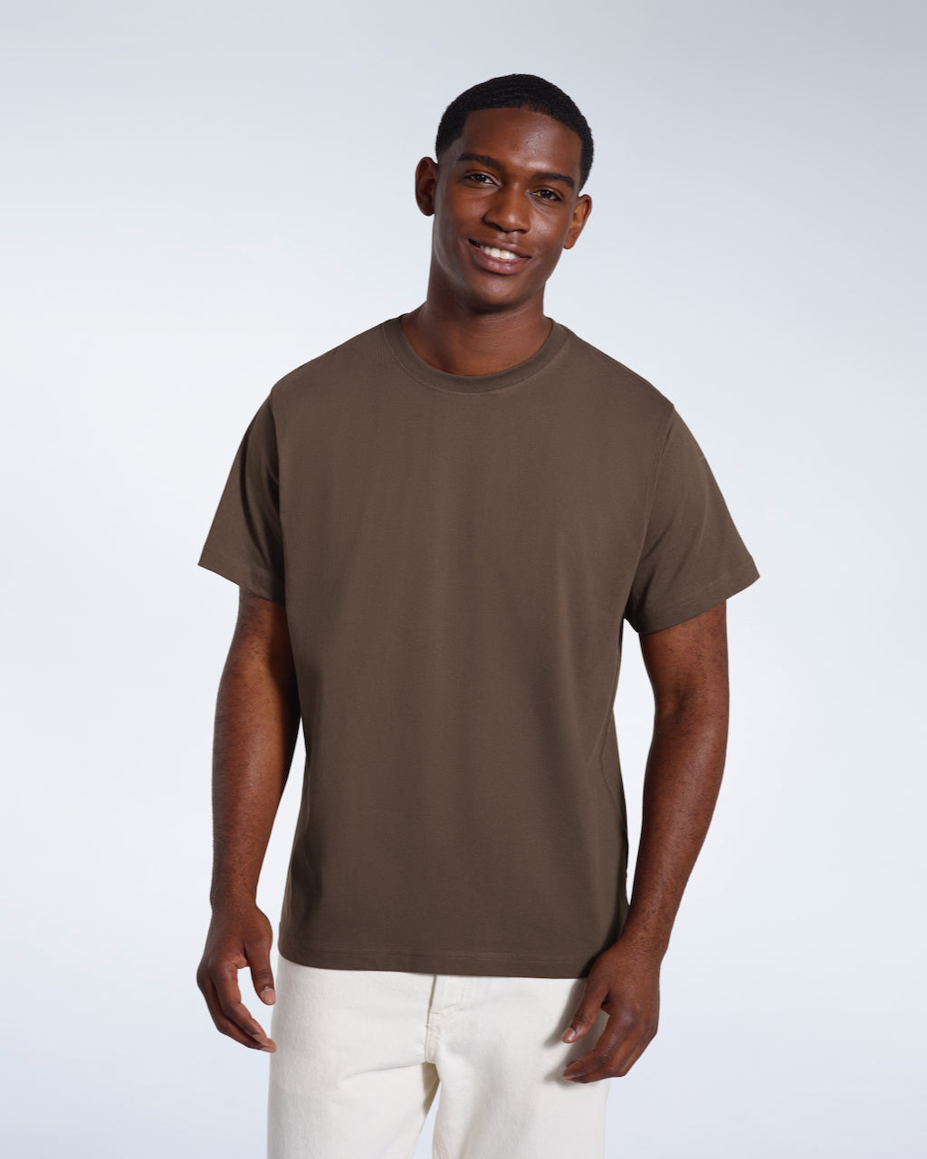 A man smiling looking into the camera, modelling a plain dark khaki short sleeve organic cotton t shirt.