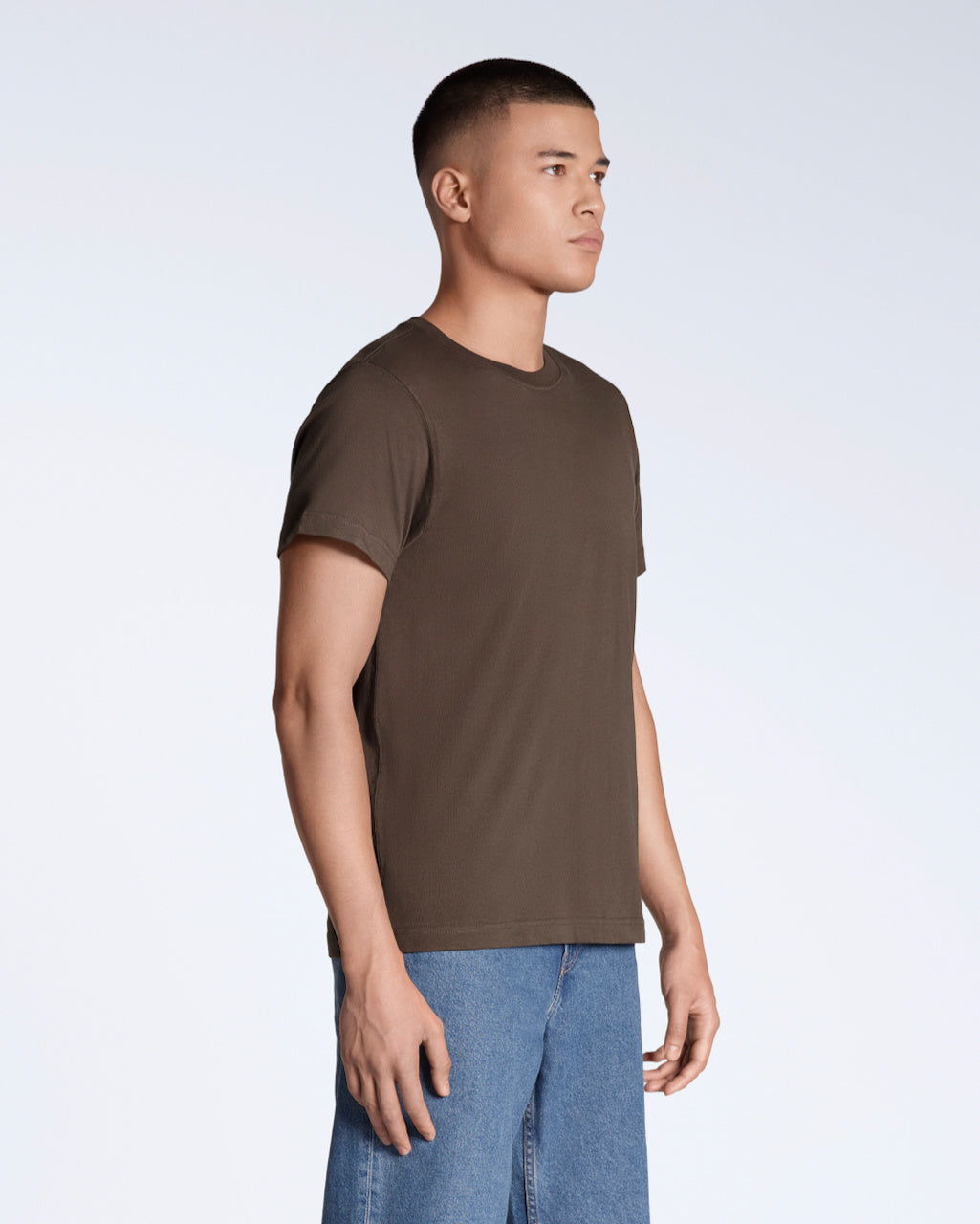 A man at an angle with his arms by his sides, modelling a plain brown short sleeve organic cotton t shirt.