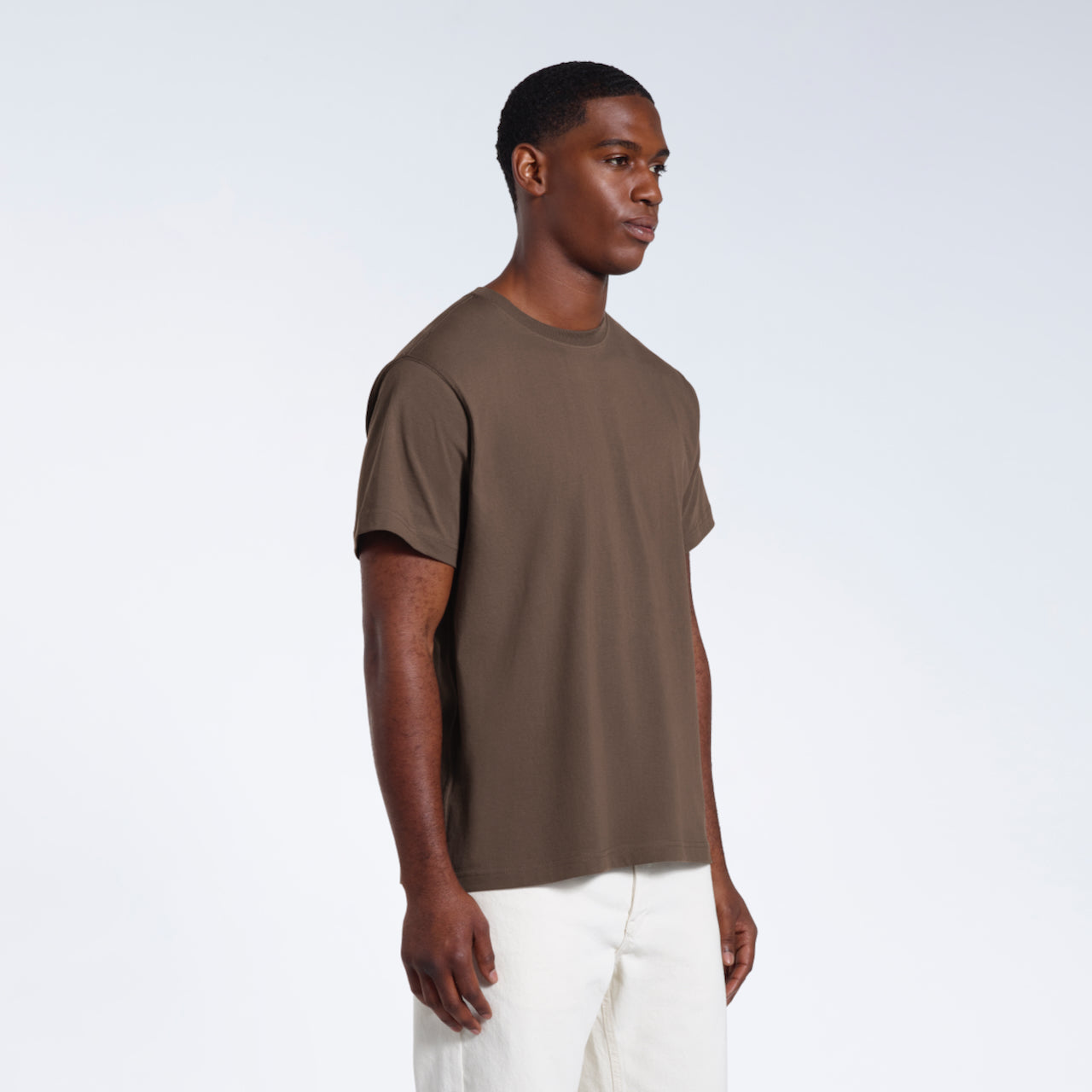 A man at an angle with his arms by his sides, modelling a plain dark khaki short sleeve organic cotton t shirt.