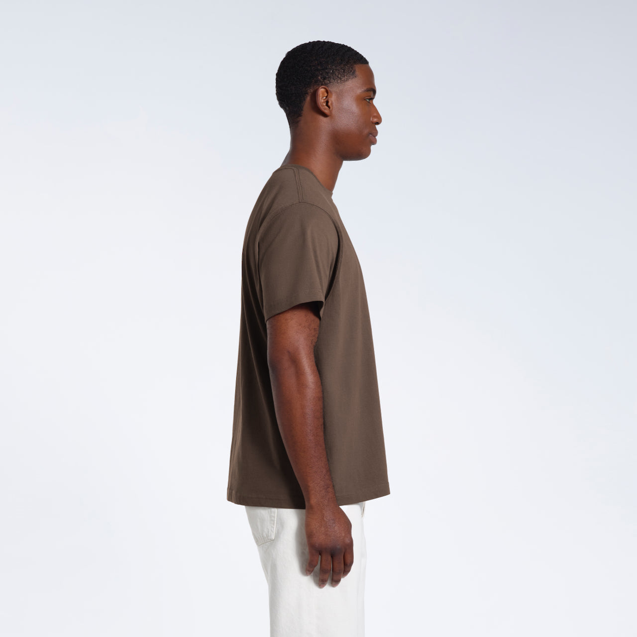 A man facing side on, modelling a plain dark khaki short sleeve organic cotton t shirt.
