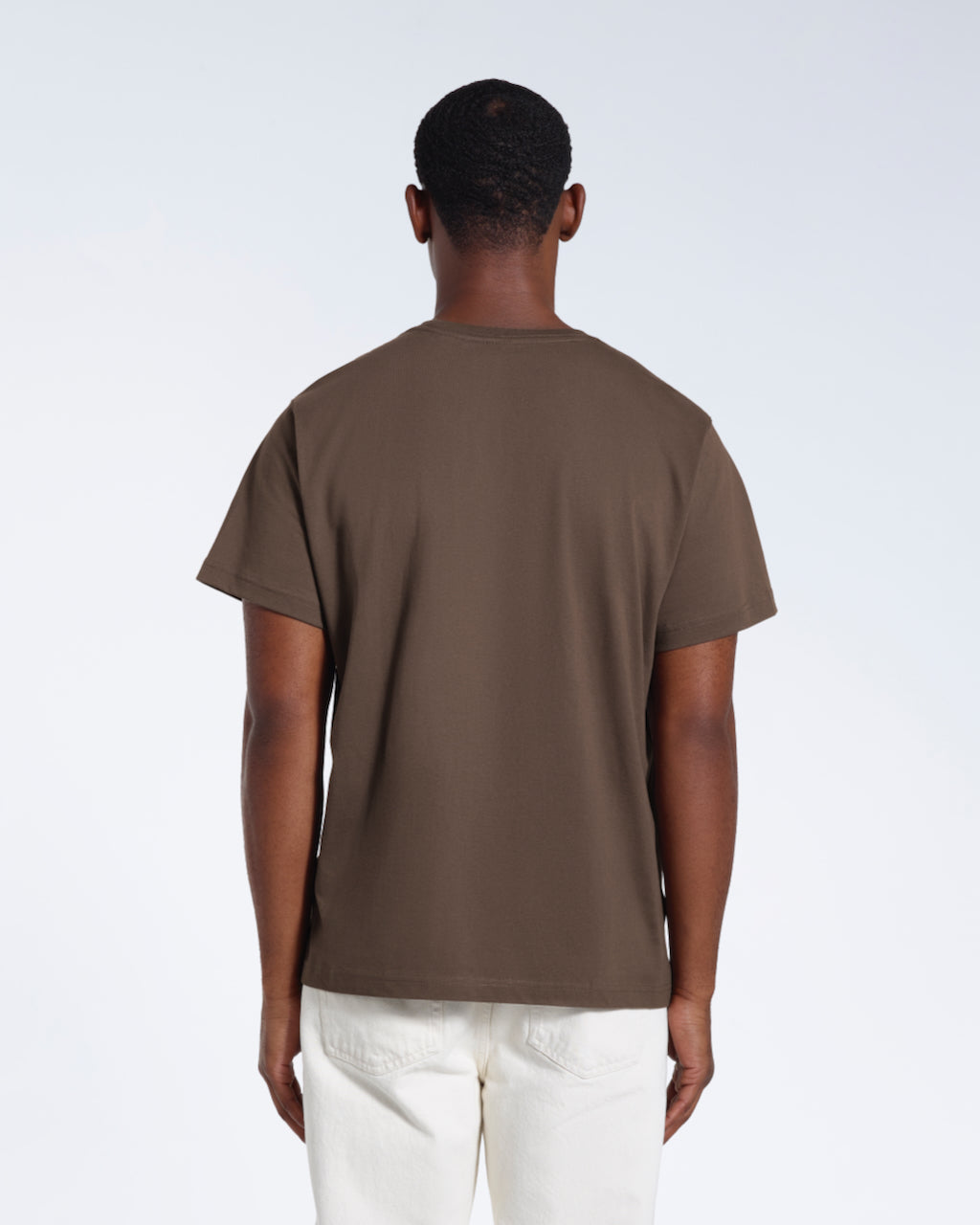 A man facing away from the camera, modelling a plain dark khaki short sleeve organic cotton t shirt.