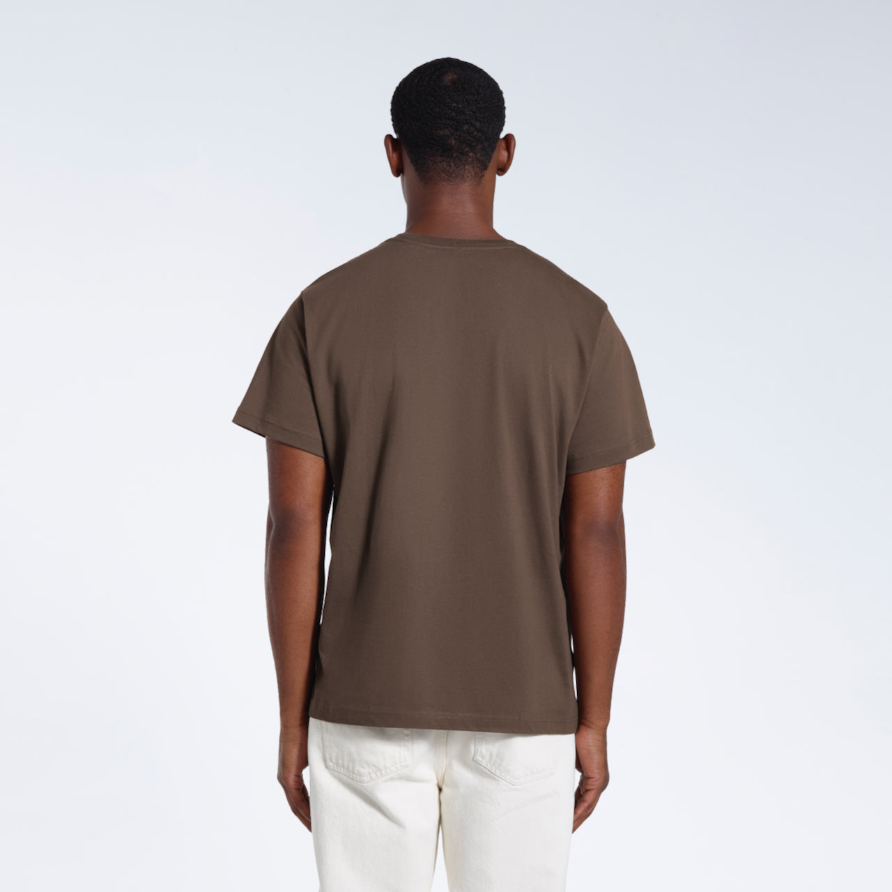 A man facing away from the camera, modelling a plain dark khaki short sleeve organic cotton t shirt.