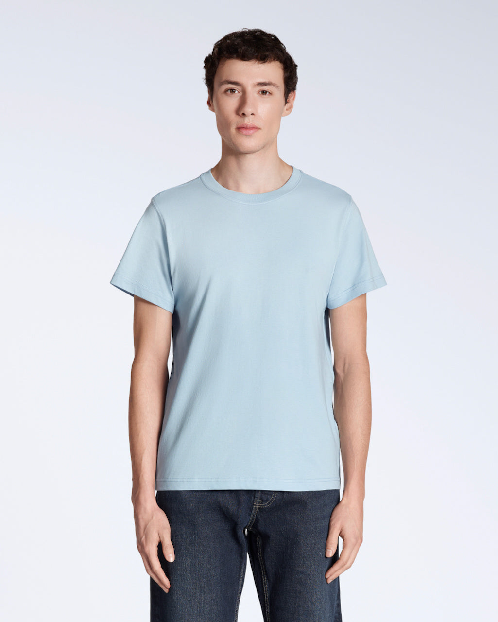 A man facing front on looking into the camera, modelling a plain light blue short sleeve organic cotton t shirt.