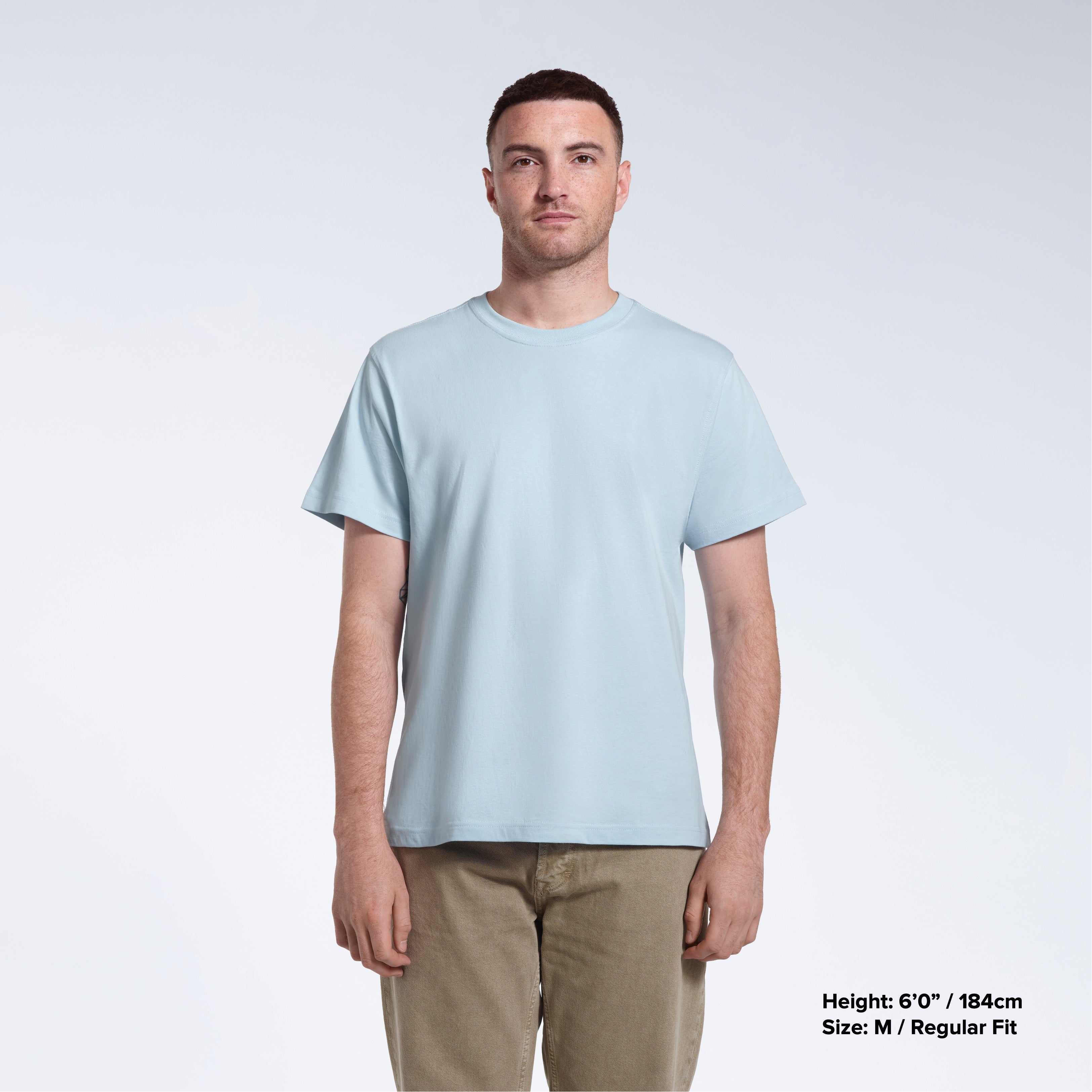 A man facing front on looking into the camera, modelling a plain light blue short sleeve organic cotton t shirt.
