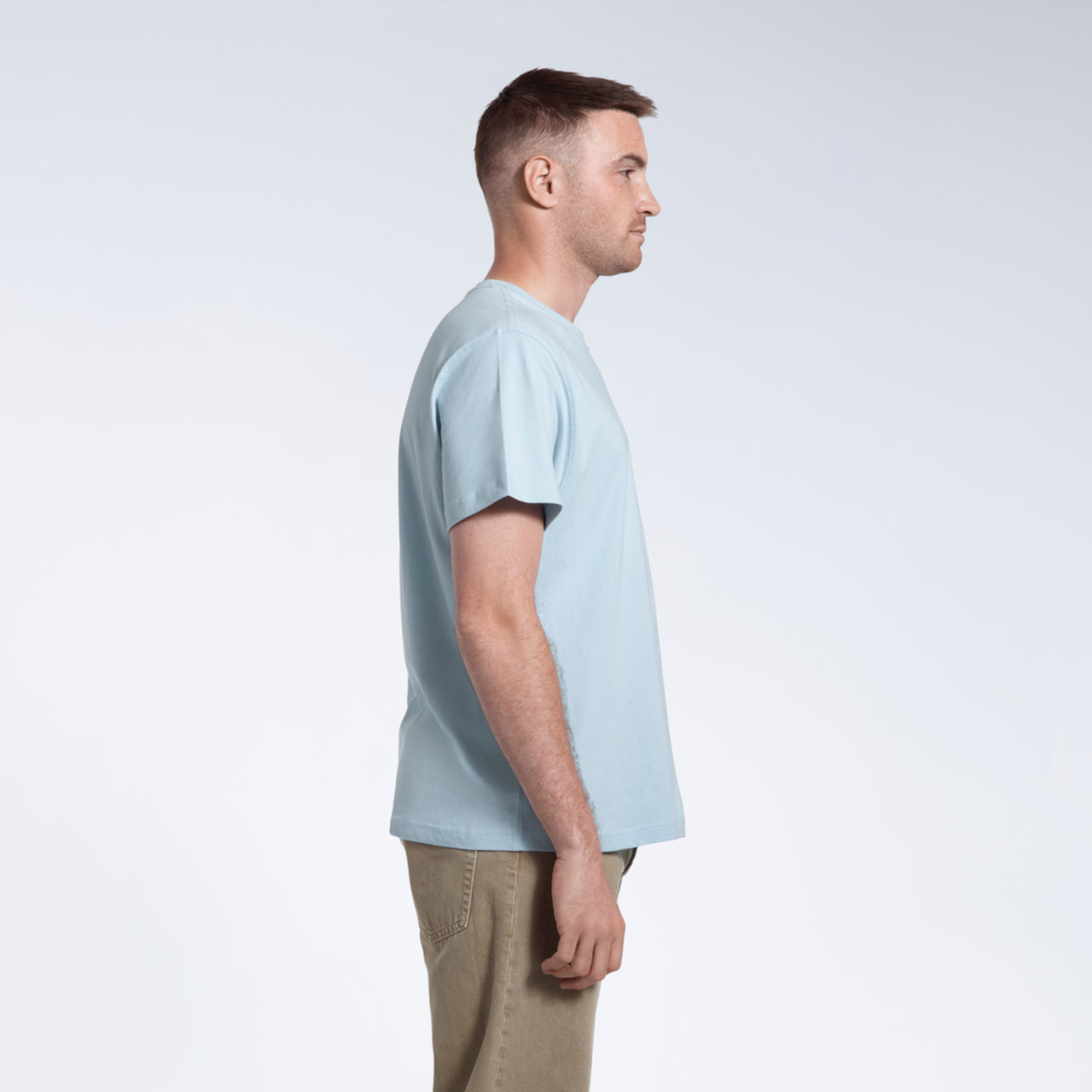 A man facing side on, modelling a plain light blue short sleeve organic cotton t shirt.