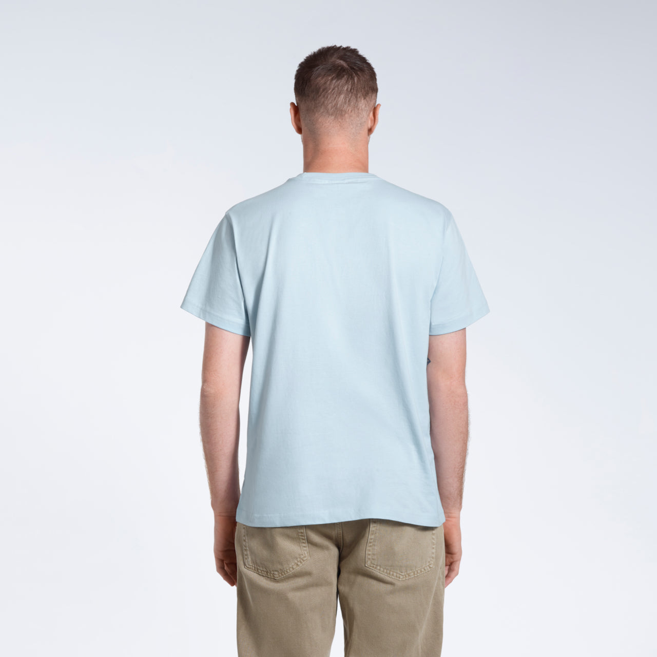 A man facing away from the camera, modelling a plain blue short sleeve organic cotton t shirt.