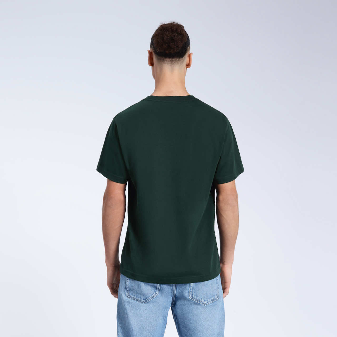 A man facing away from the camera, modelling a plain green short sleeve organic cotton t shirt.