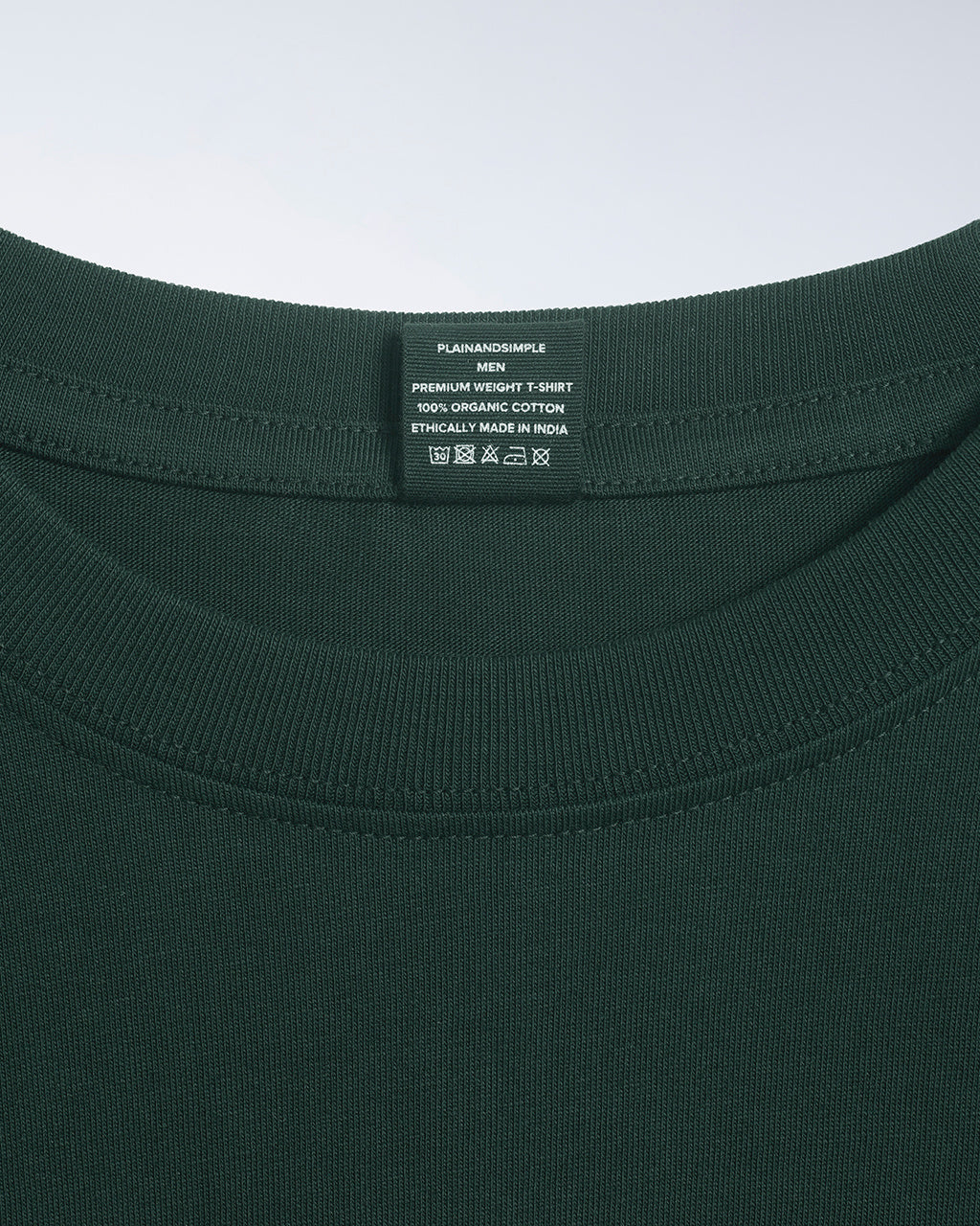 A close up of an neck label in a men's green short sleeve crew neck organic cotton t shirt.