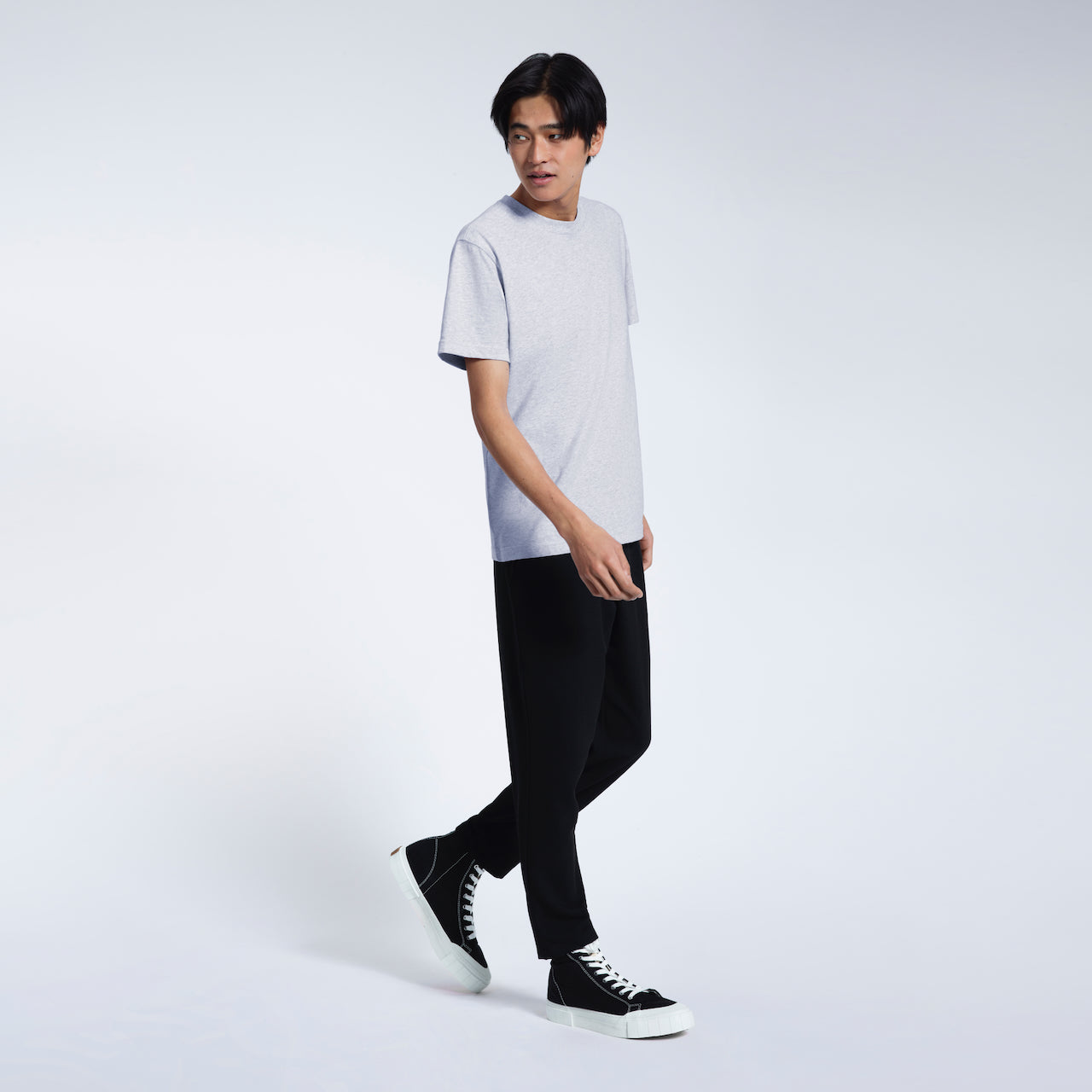 A full body photo of a man walking, modelling a grey short sleeve organic cotton t shirt.