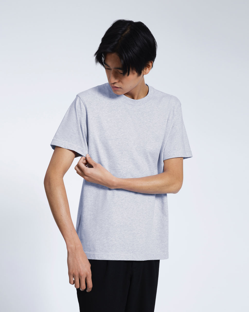 A man looking down touching his sleeve, modelling a plain grey short sleeve organic cotton t shirt.