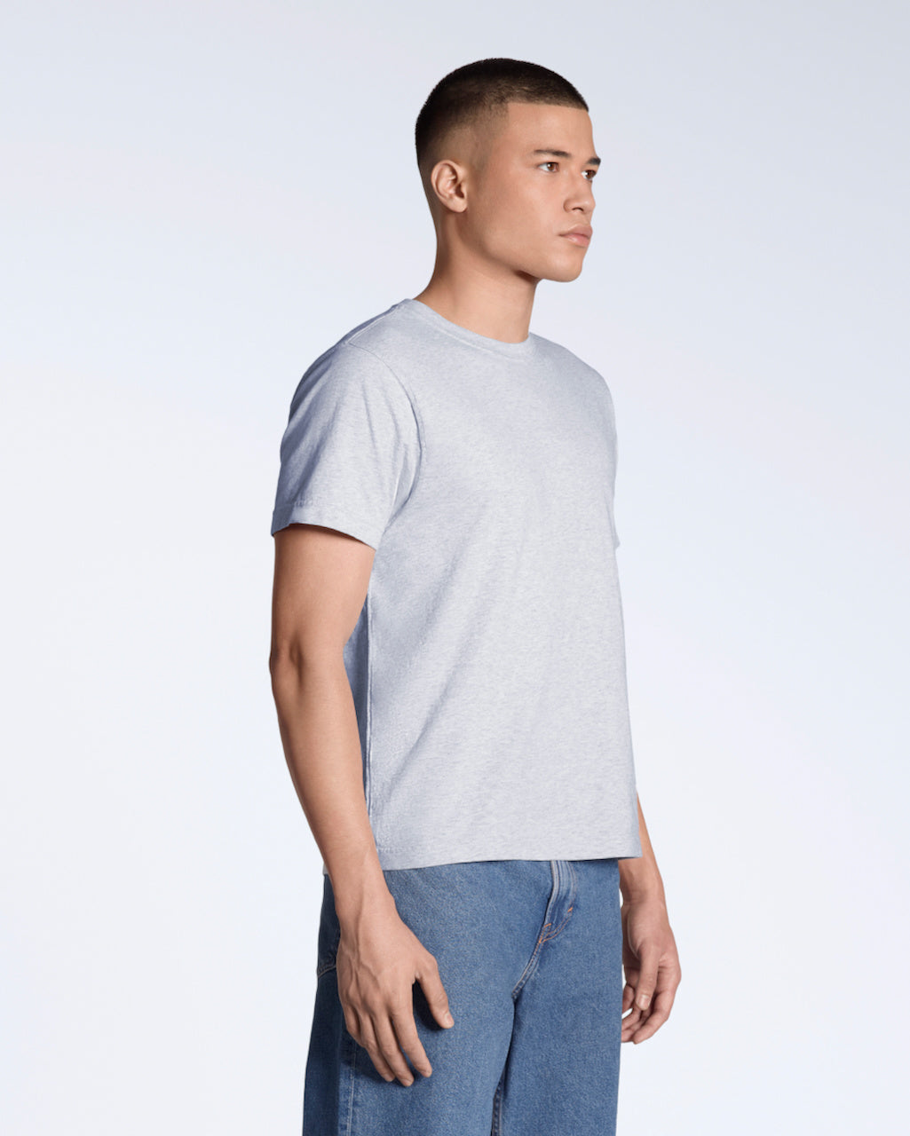 A man at an angle with his arms by his sides, modelling a plain grey short sleeve organic cotton t shirt.