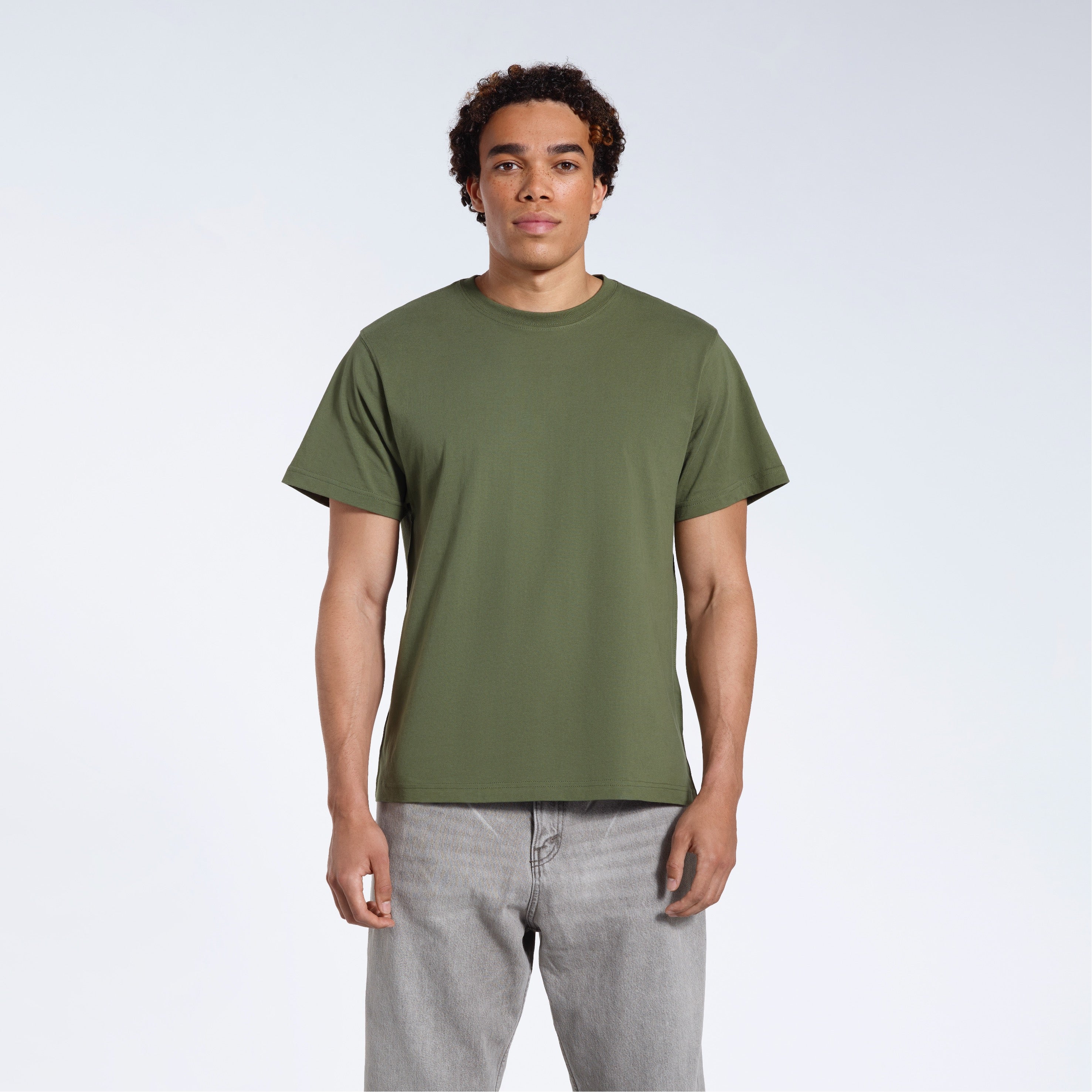 A man facing front on looking into the camera, modelling a plain khaki green short sleeve organic cotton t shirt.