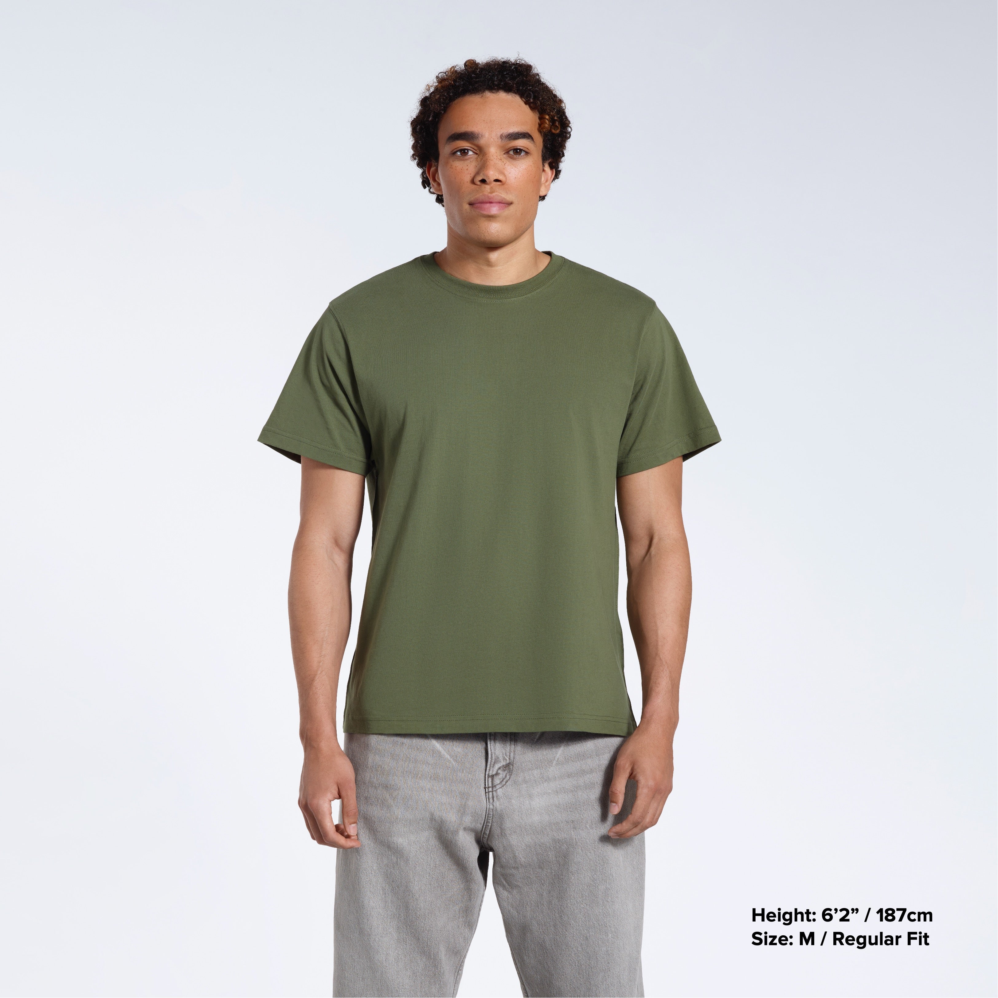 A man facing front on looking into the camera, modelling a plain khaki green short sleeve organic cotton t shirt.