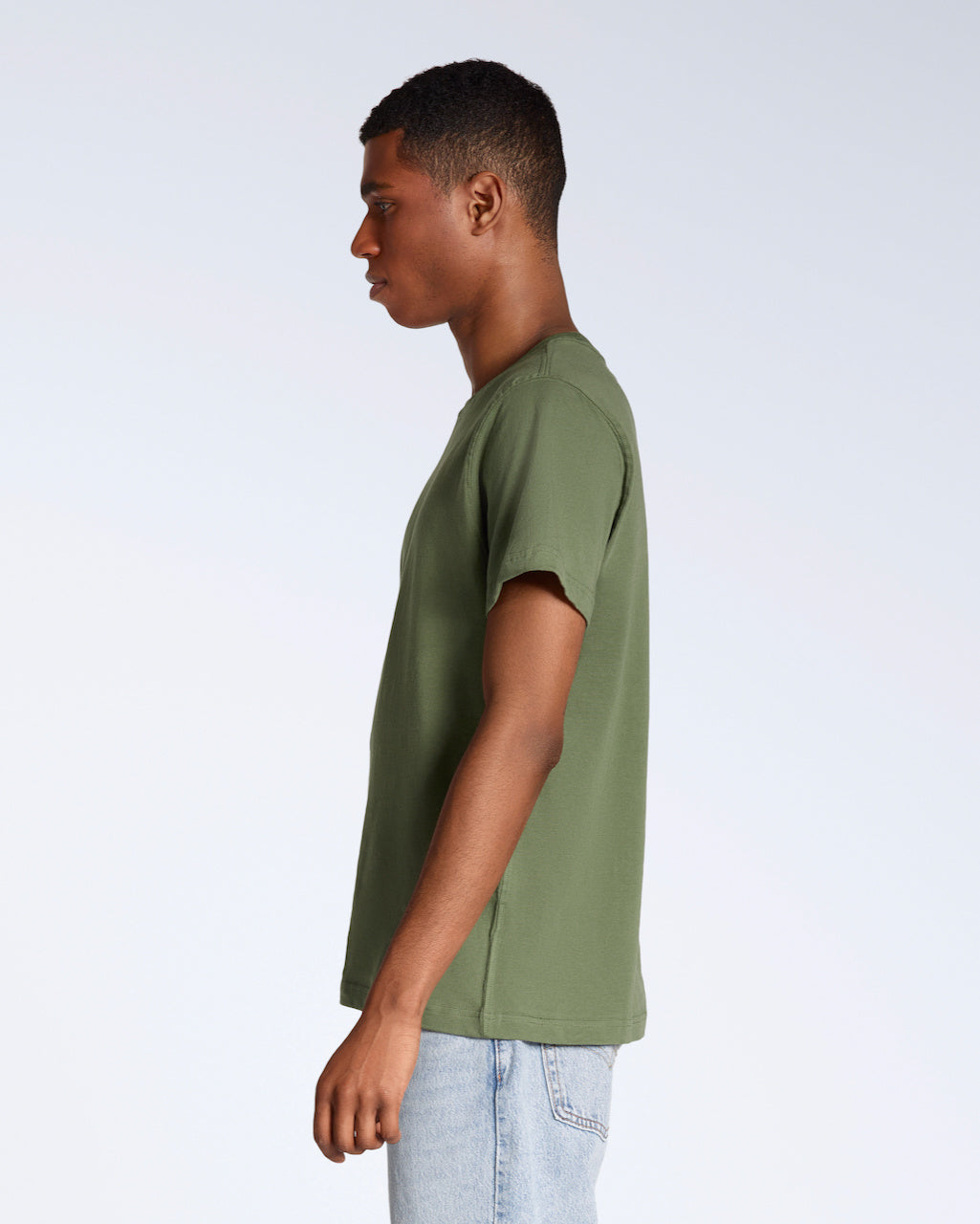 A man facing side on, modelling a plain khaki green short sleeve organic cotton t shirt.