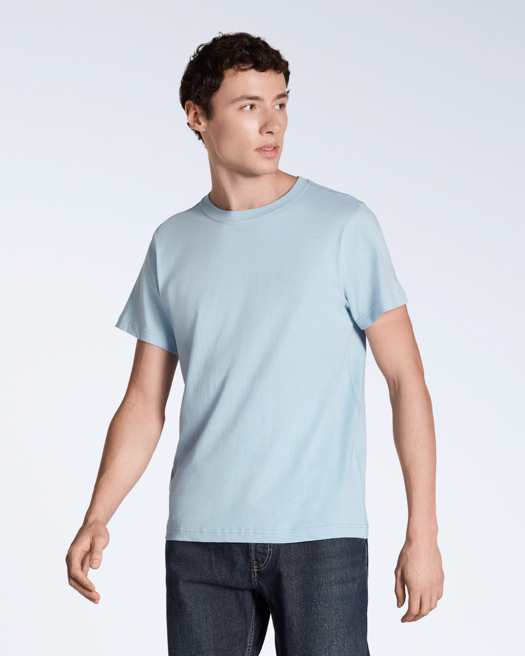 A man looking away from the camera, modelling a plain light blue short sleeve organic cotton t shirt.