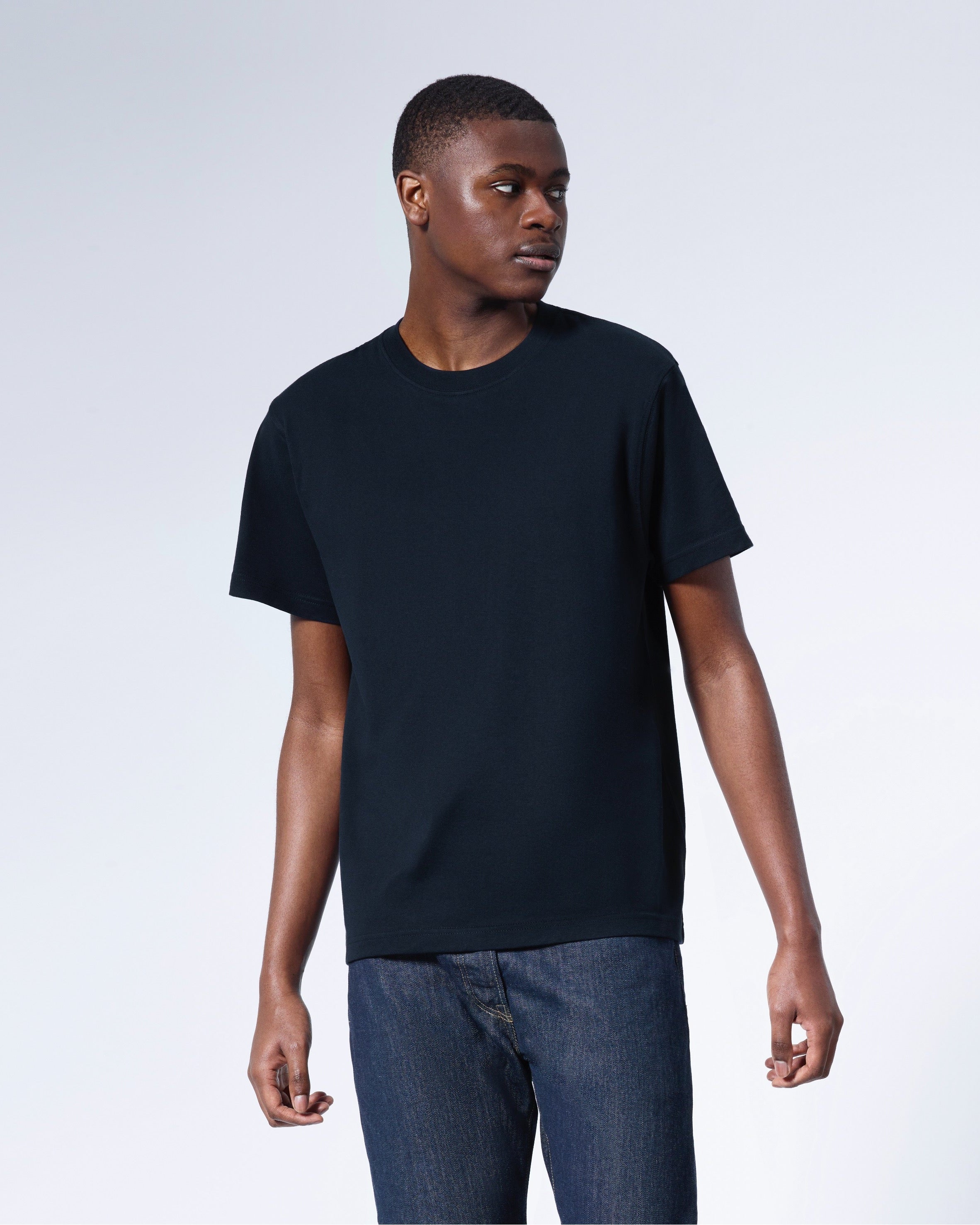 A man looking away from the camera, modelling a plain navy short sleeve organic cotton t shirt.