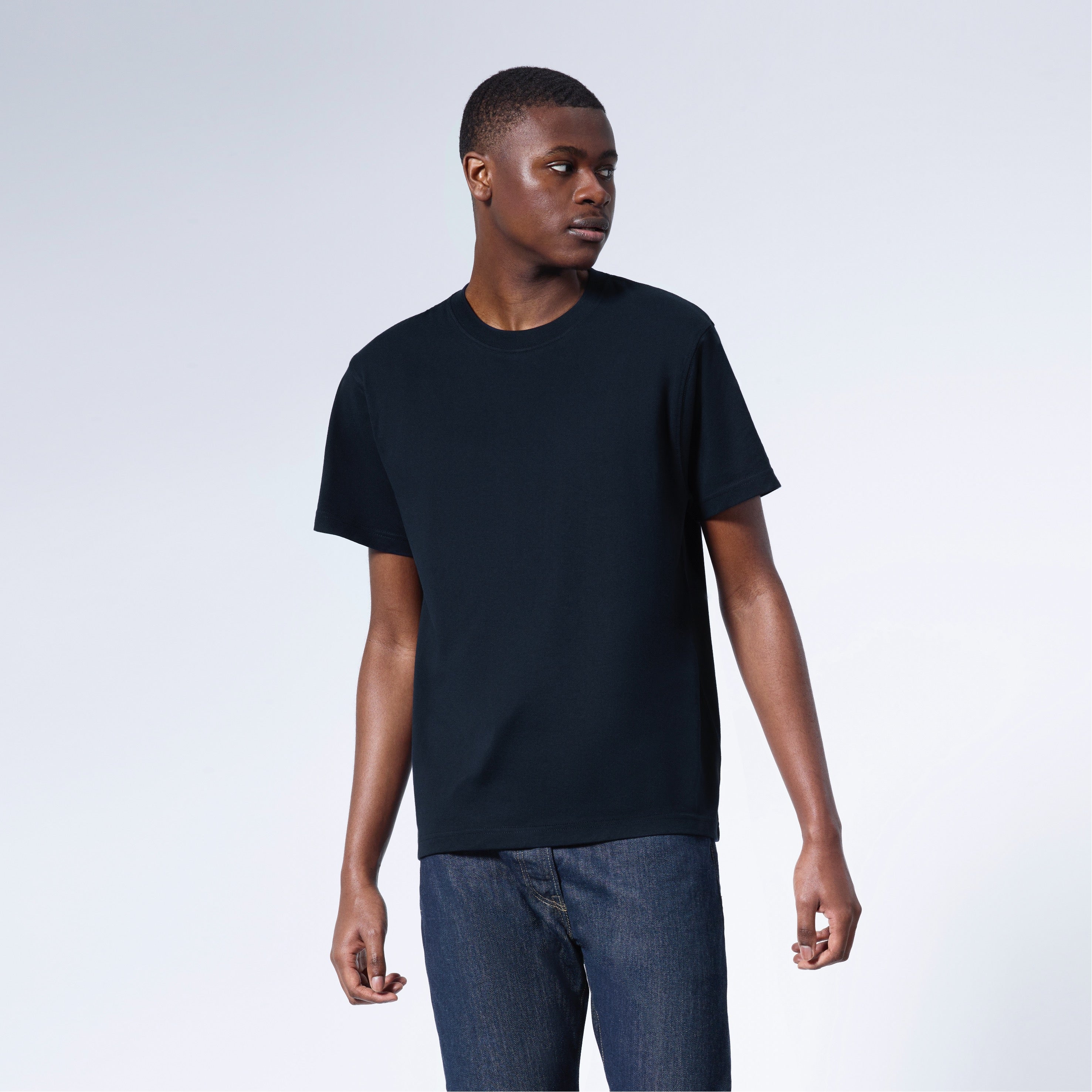 A man looking away from the camera, modelling a plain navy short sleeve organic cotton t shirt.