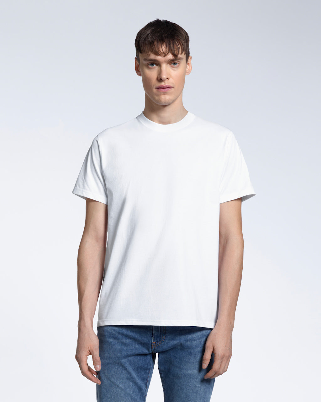 A man facing front on looking into the camera, modelling a plain white short sleeve organic cotton t shirt.