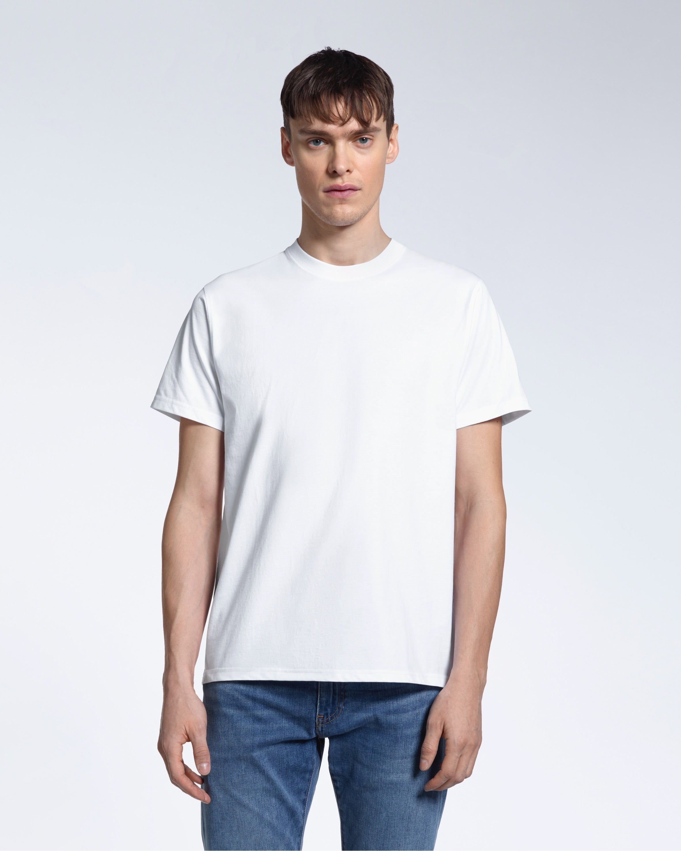 A man facing front on looking into the camera, modelling a plain white short sleeve organic cotton t shirt.