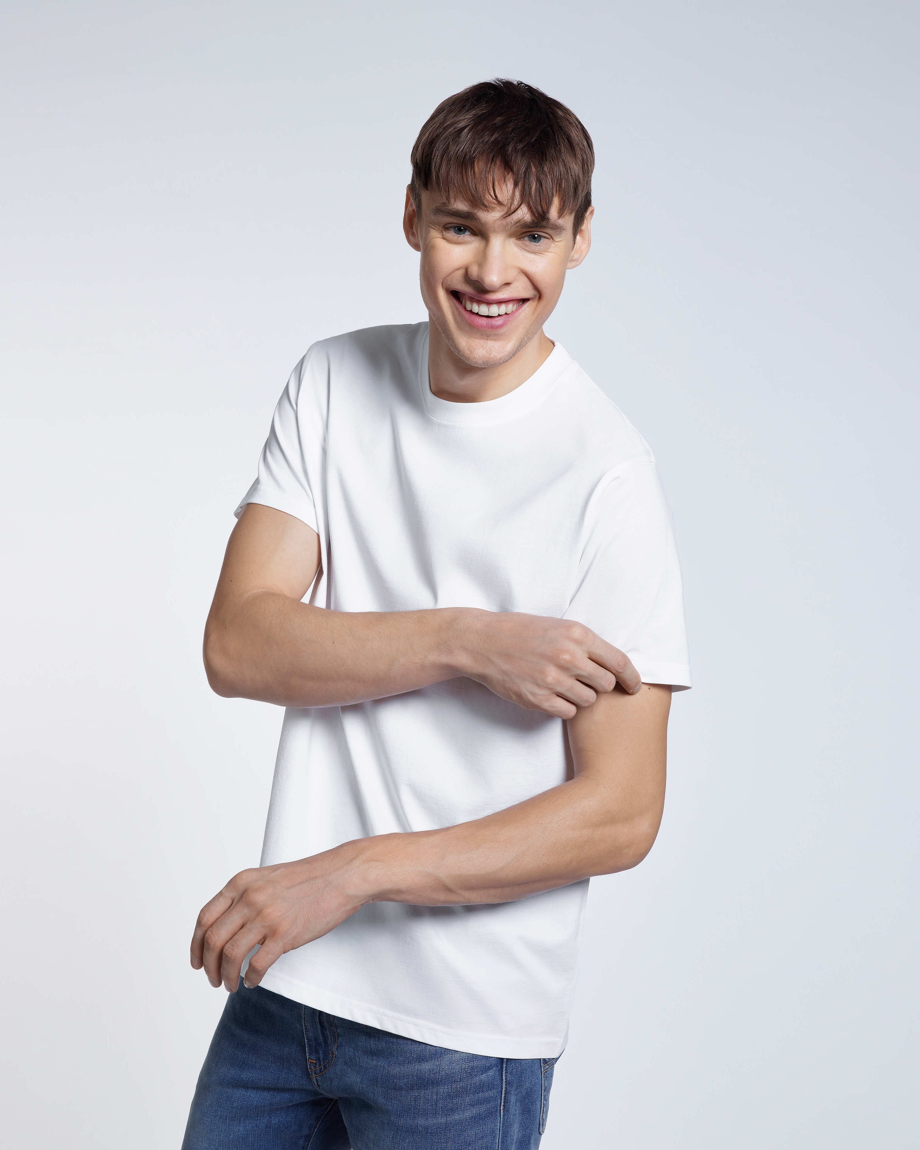 A man smiling touching his sleeve, modelling a plain white short sleeve organic cotton t shirt.