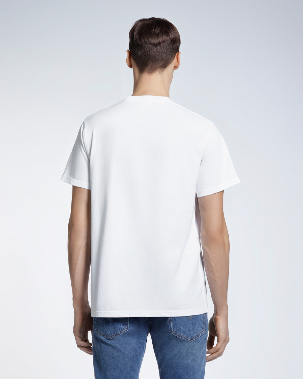 A man facing away from the camera, modelling a plain white short sleeve organic cotton t shirt.