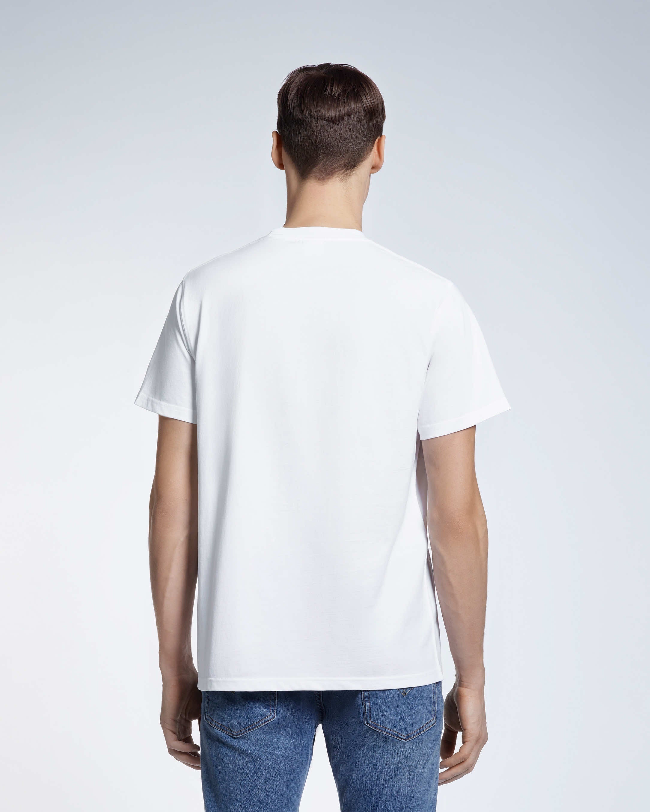 A man facing away from the camera, modelling a plain white short sleeve organic cotton t shirt.