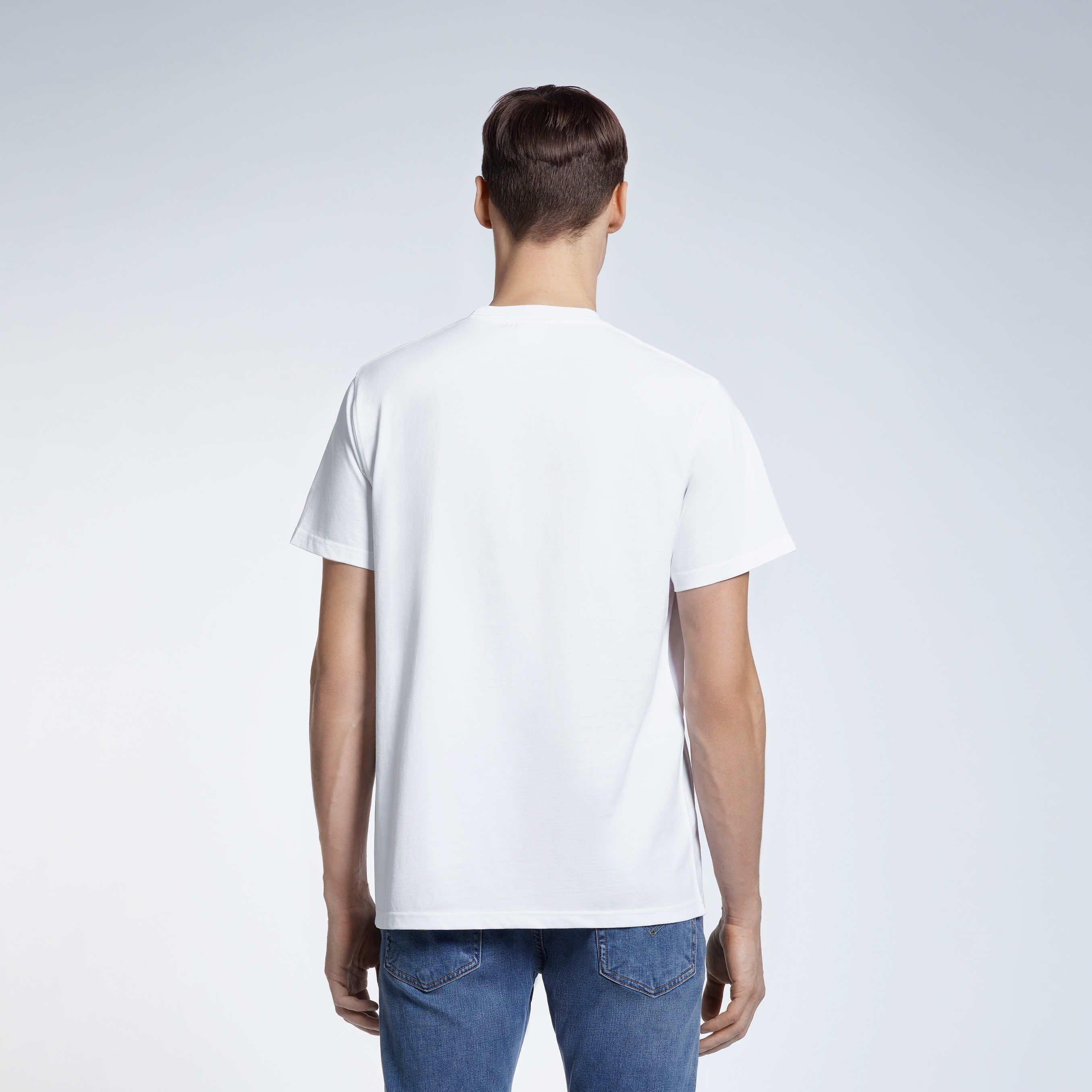 A man facing away from the camera, modelling a plain white short sleeve organic cotton t shirt.