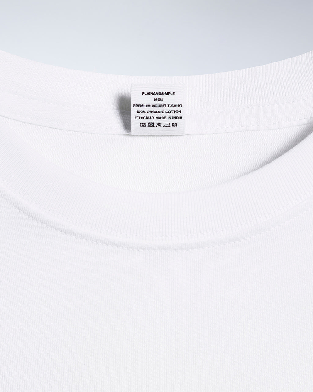 A close up of a neck label in a men's white, premium weight, organic cotton t shirt.