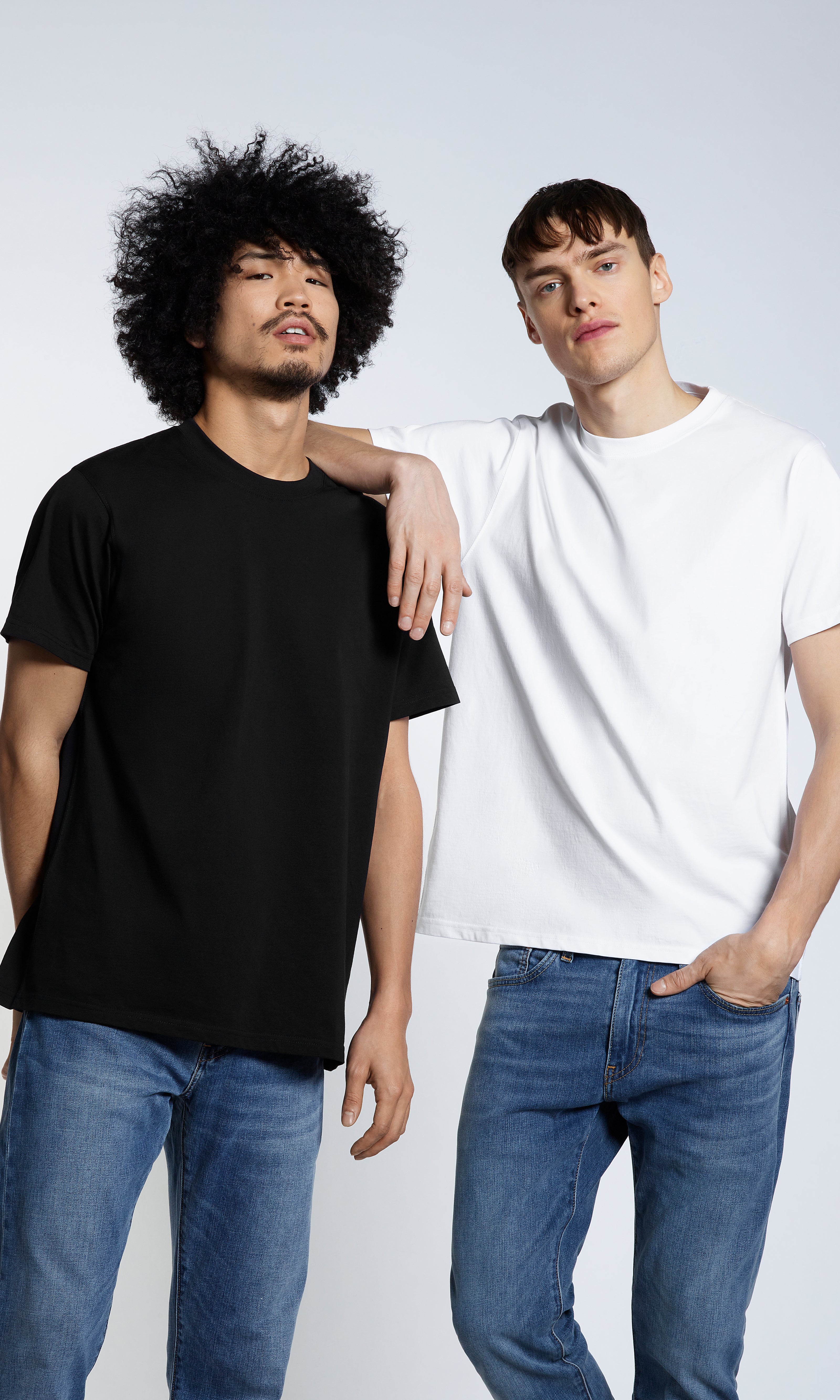 Two men looking into the camera, modelling plain black and white organic cotton t shirts.