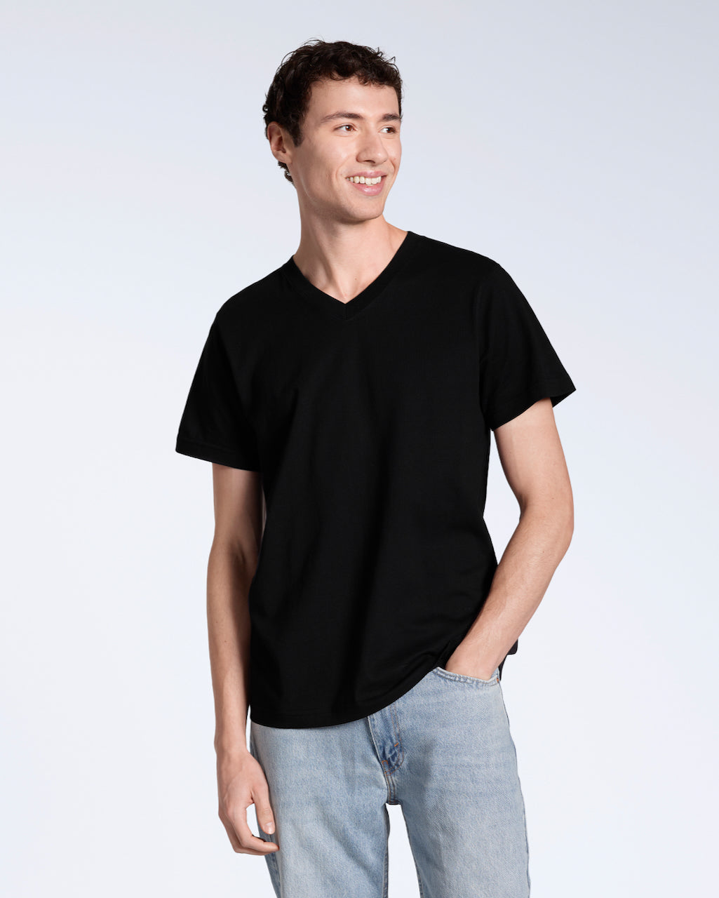 A man looking into the camera with his hand in his pocket, modelling a plain black, organic cotton v neck t shirt.