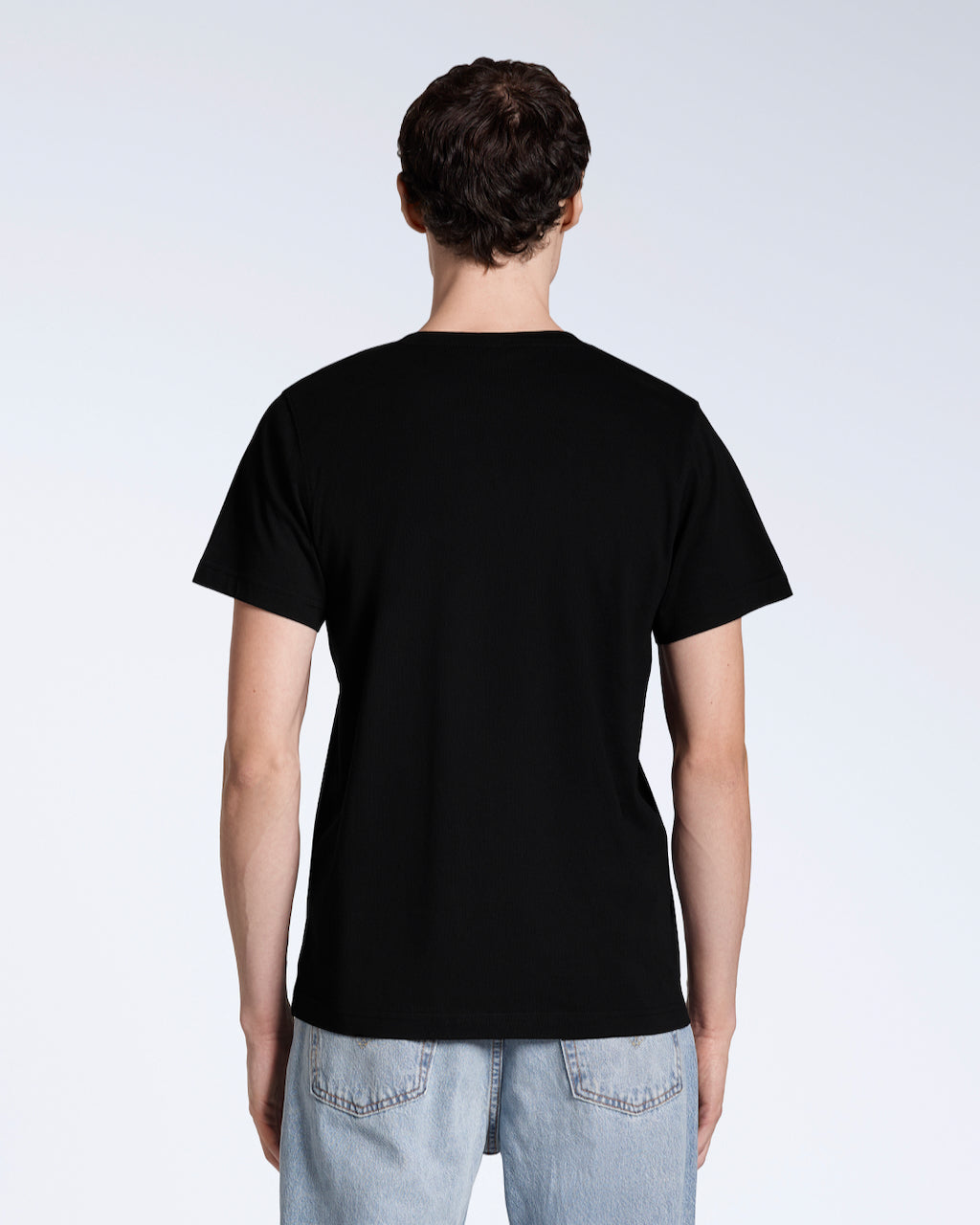 A man facing away from the camera, modelling a plain black, organic cotton v neck t shirt.