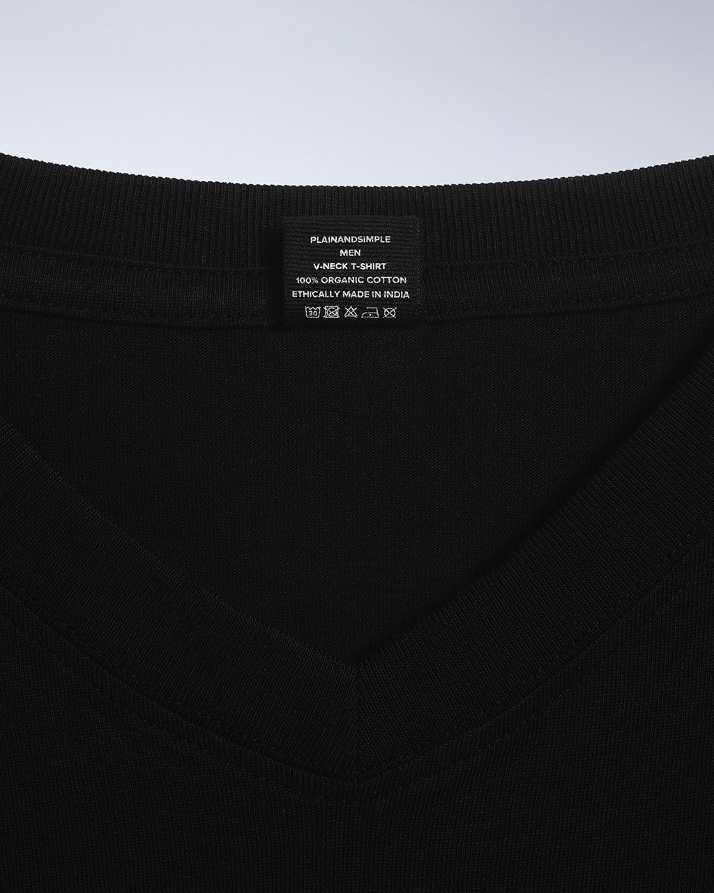 A close up of a neck label in a men's black, organic cotton, v neck t shirt.