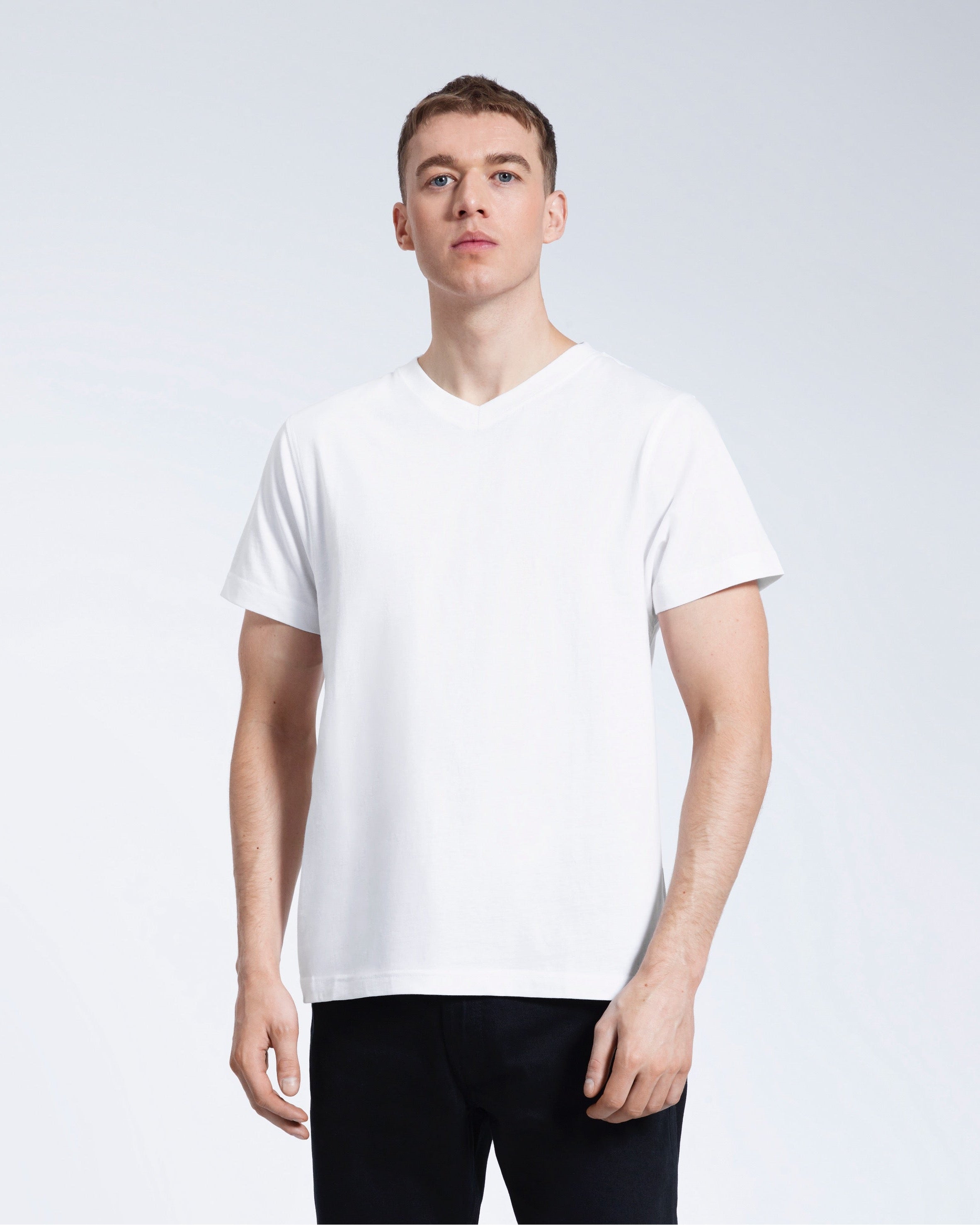 A man facing front on with his arms by his sides, modelling a plain white organic cotton v neck t shirt.