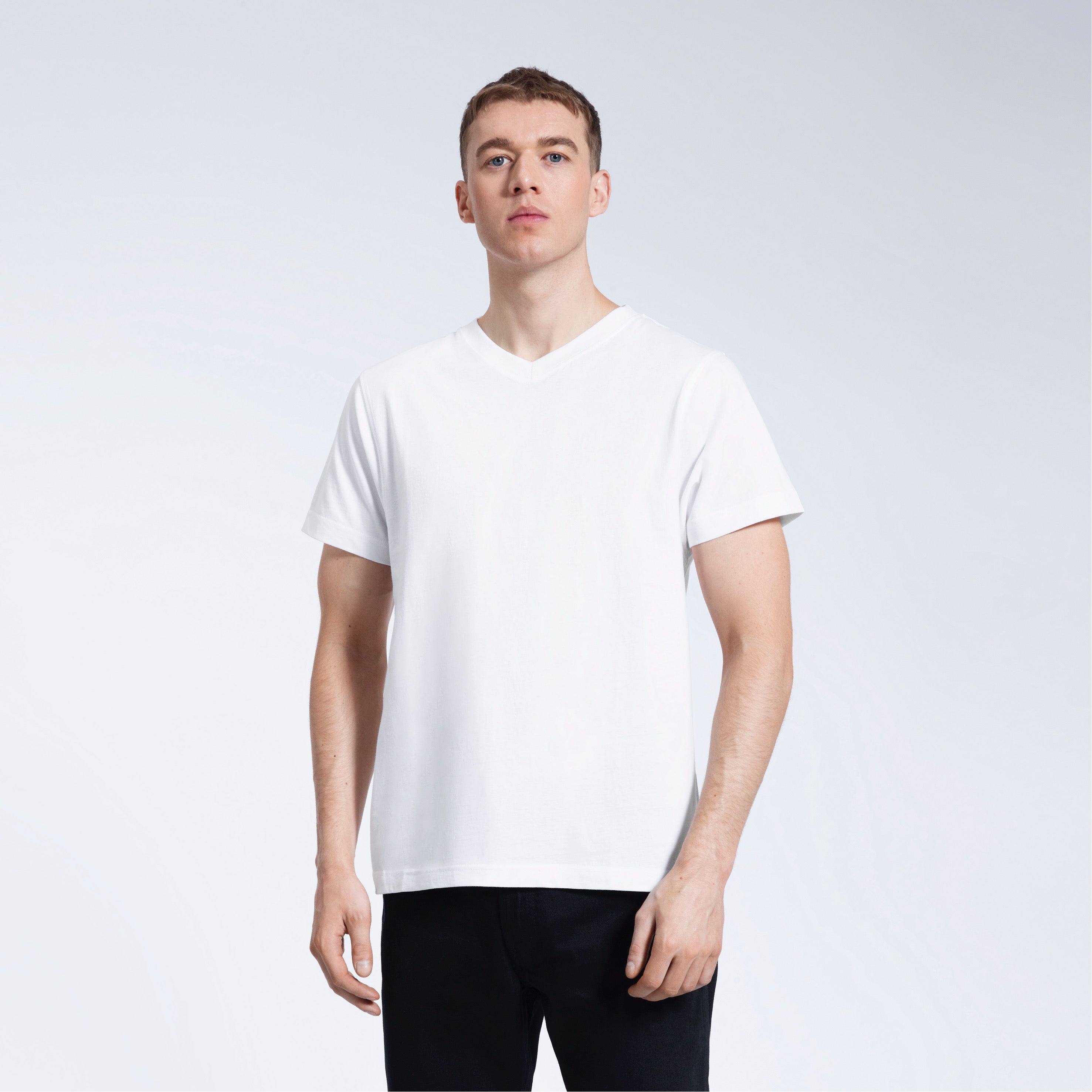 A man facing front on with his arms by his sides, modelling a plain white organic cotton v neck t shirt.