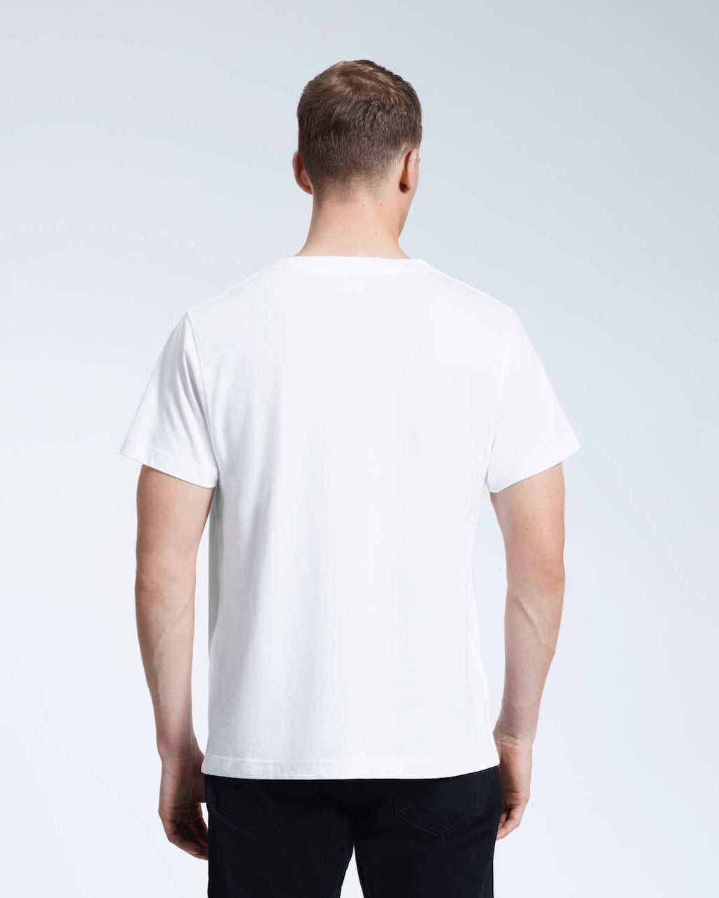A man facing away from the camera with his arms by his sides, modelling a plain white organic cotton v neck t shirt.