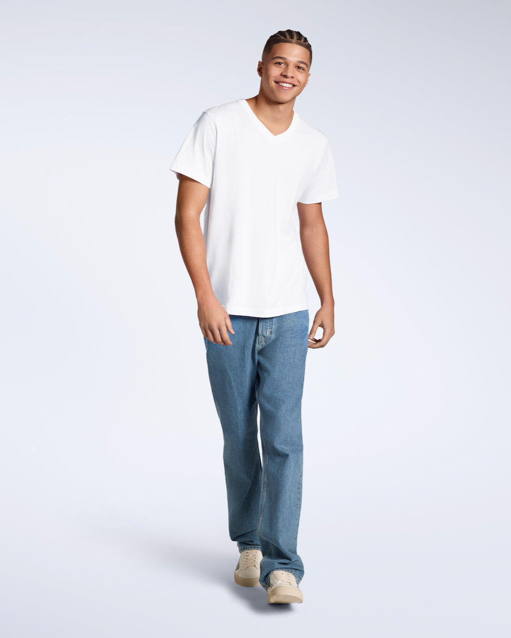 A full body photo of a man smiling into the camera, modelling a plain white, organic cotton v neck t shirt with a pair of blue jeans.