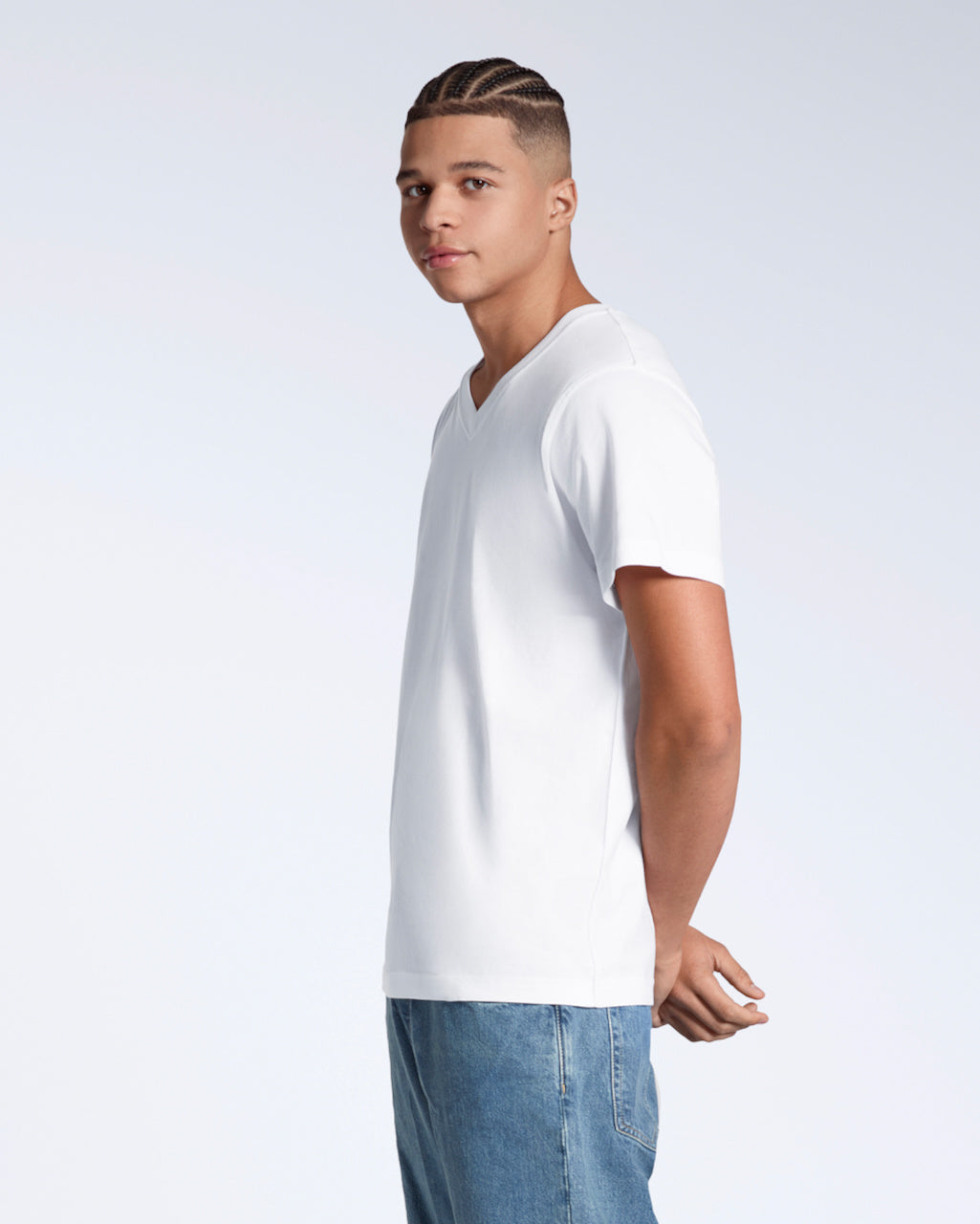 A man facing side on looking into the camera with, modelling a plain white, organic cotton v neck t shirt.