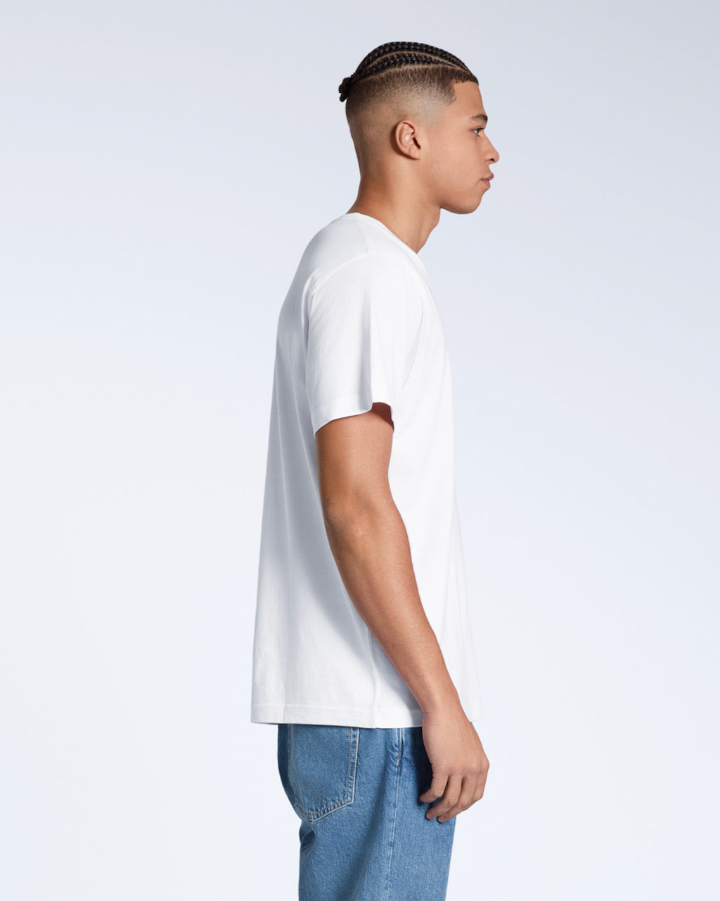 A man facing side on, with his arms by his side, modelling a plain white, organic cotton v neck t shirt.