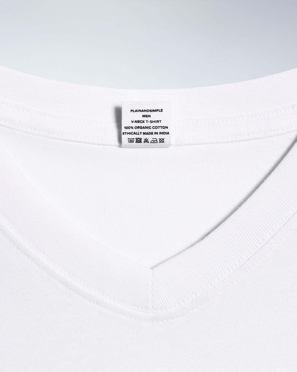 A close up of a neck label in a men's white, organic cotton, v neck t shirt.