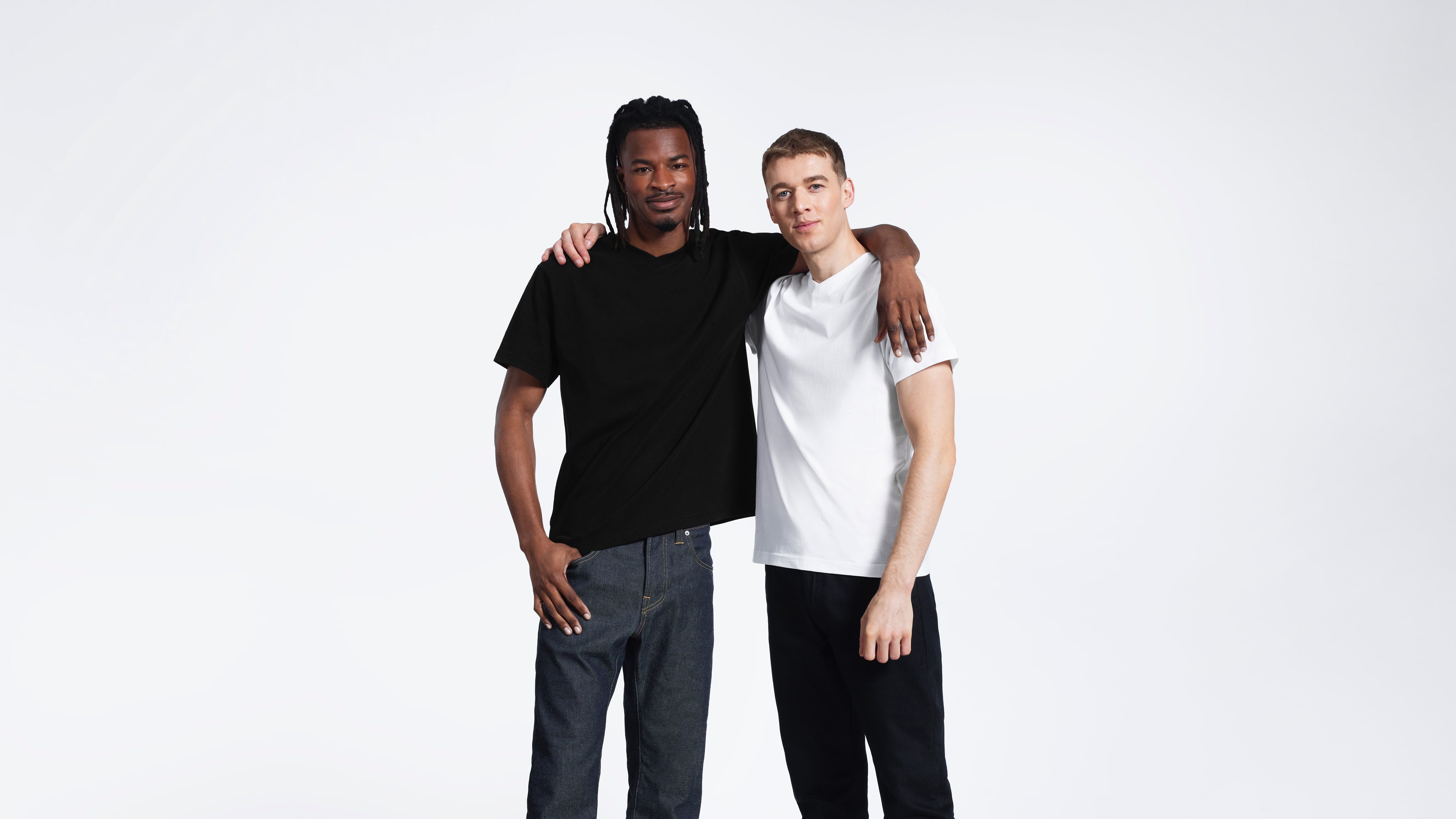 Two men with their arms round each other, modelling plain black and white organic cotton v neck t shirts.