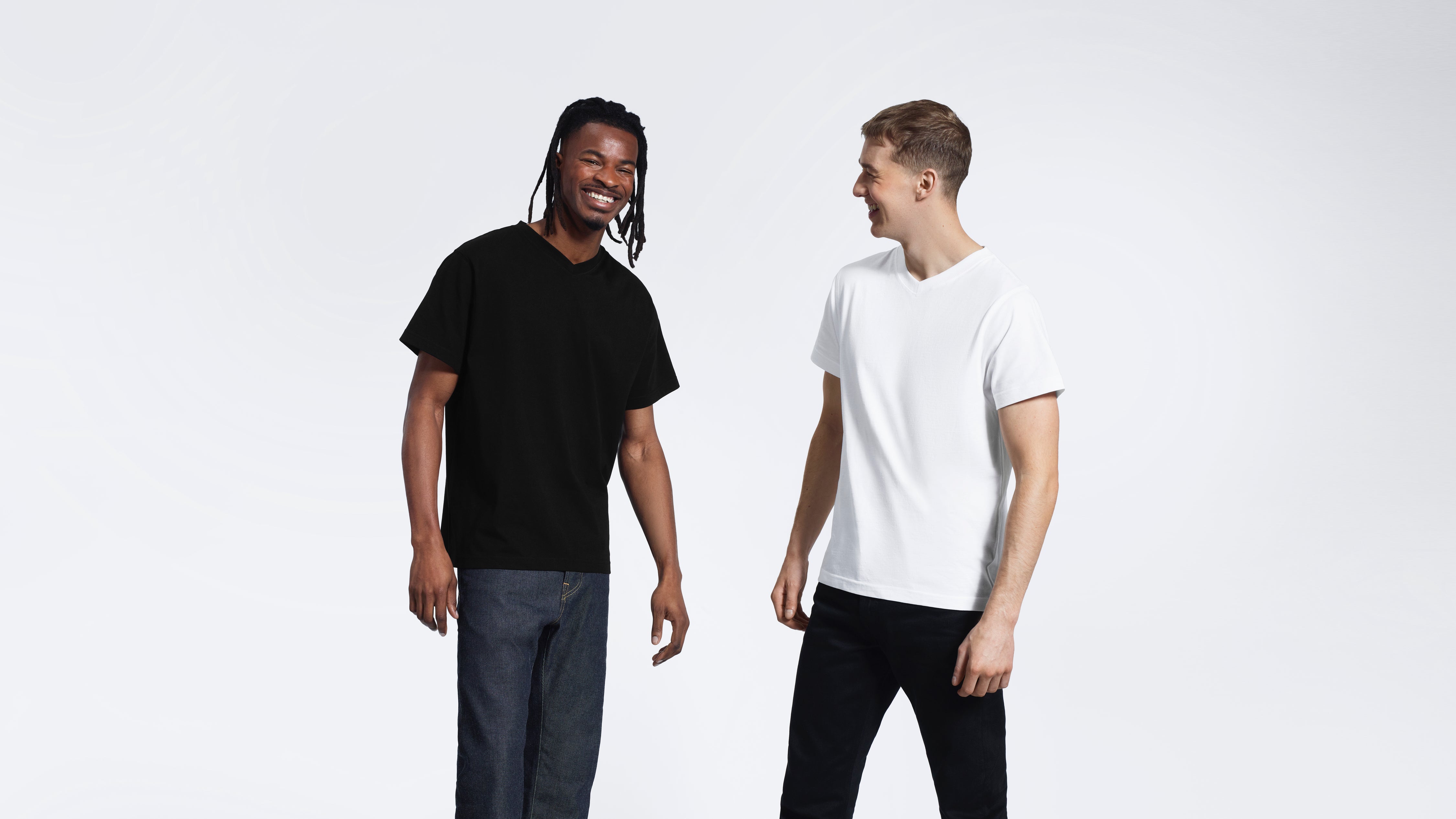 Two men laughing, modelling plain black and white organic cotton v neck t shirts.