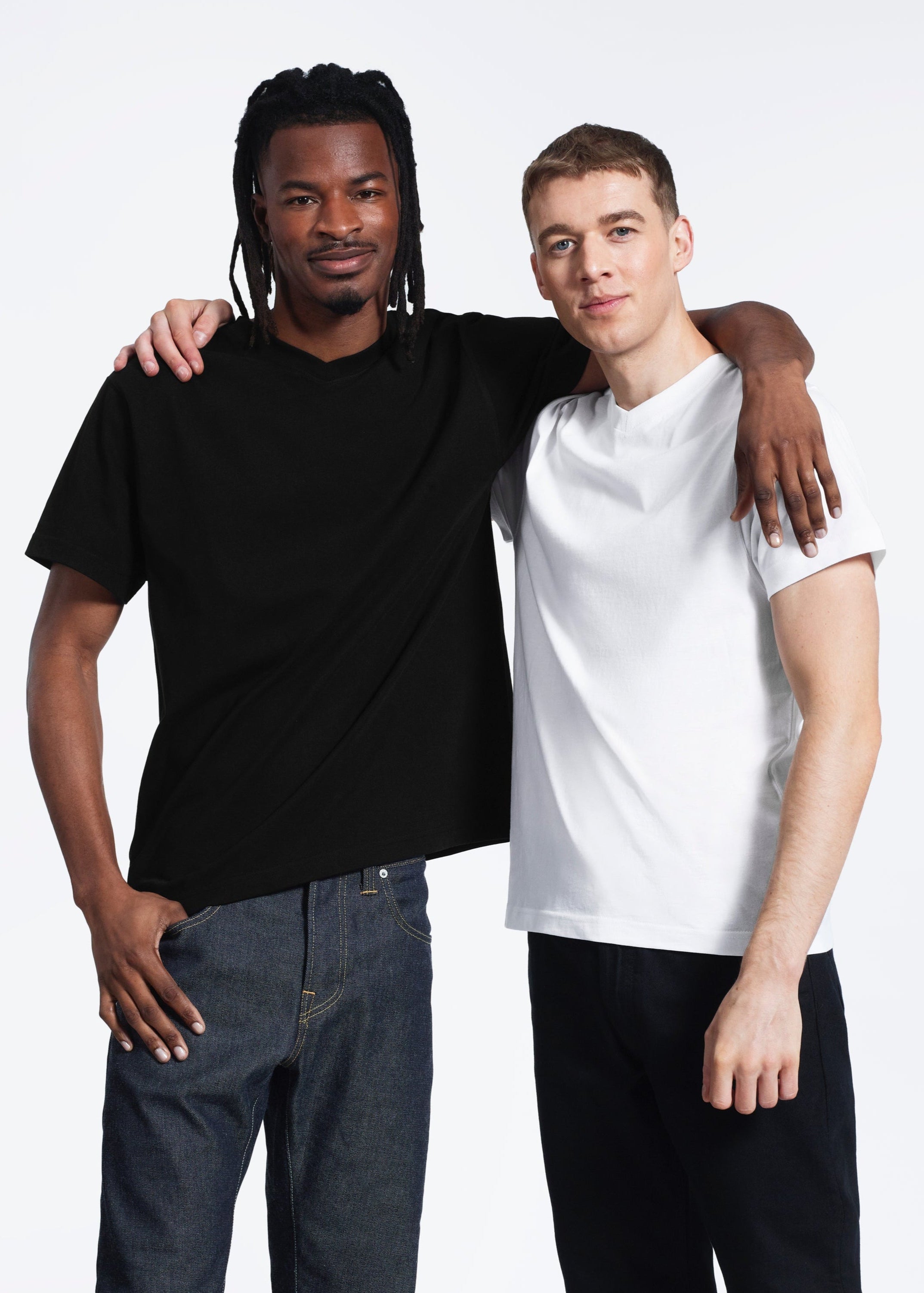 Two men with their arms round each other, modelling plain black and white organic cotton v neck t shirts.