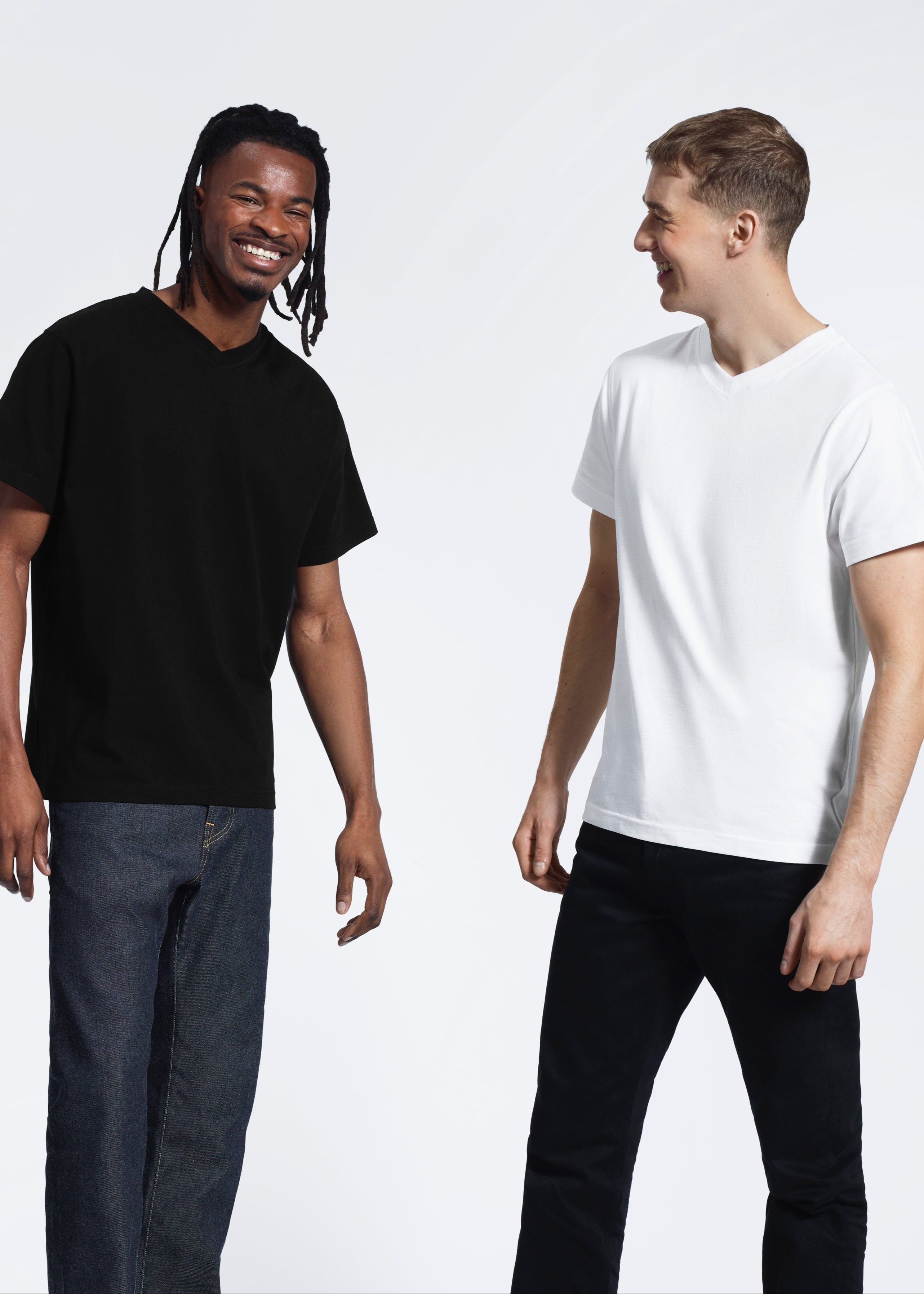 Two men laughing, modelling plain black and white organic cotton v neck t shirts.