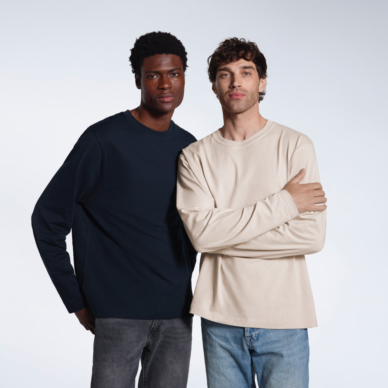 Two men looking at the camera, modelling plain navy and stone coloured long sleeve, organic cotton t shirts.