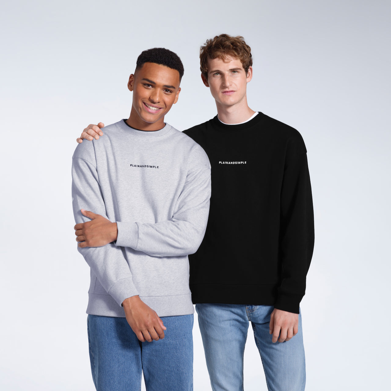 Two men looking at the camera, modelling branded black and grey heavyweight, organic cotton sweatshirts.
