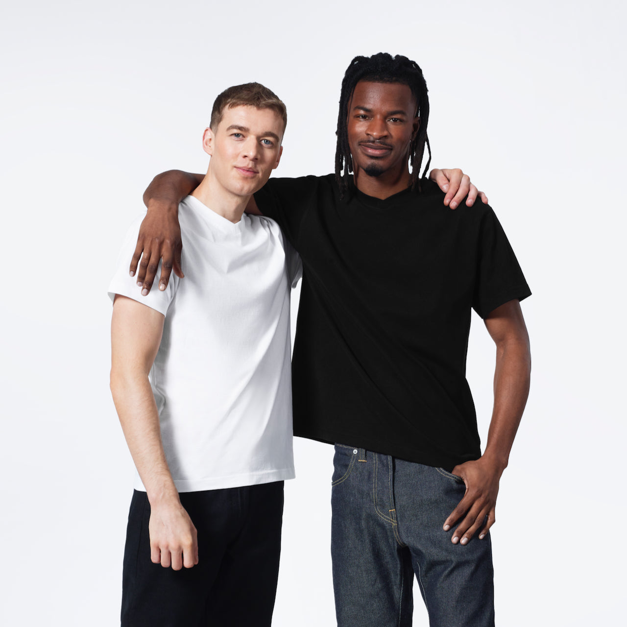 Two men with their arms round eachother, modelling plain black and white, organic cotton v neck t shirts.
