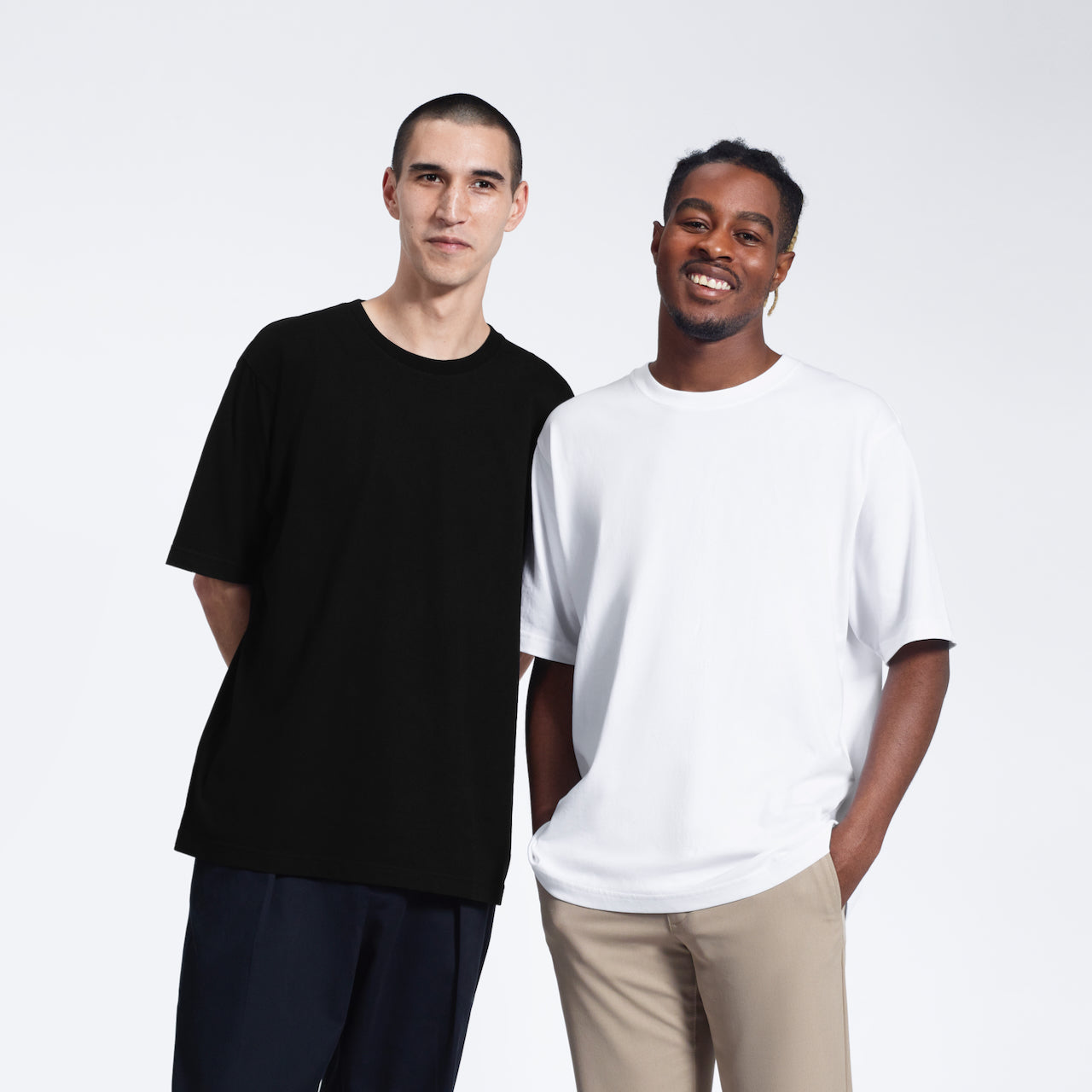 Two men smiling, modelling plain oversized black and white, heavyweight, organic cotton t shirts.